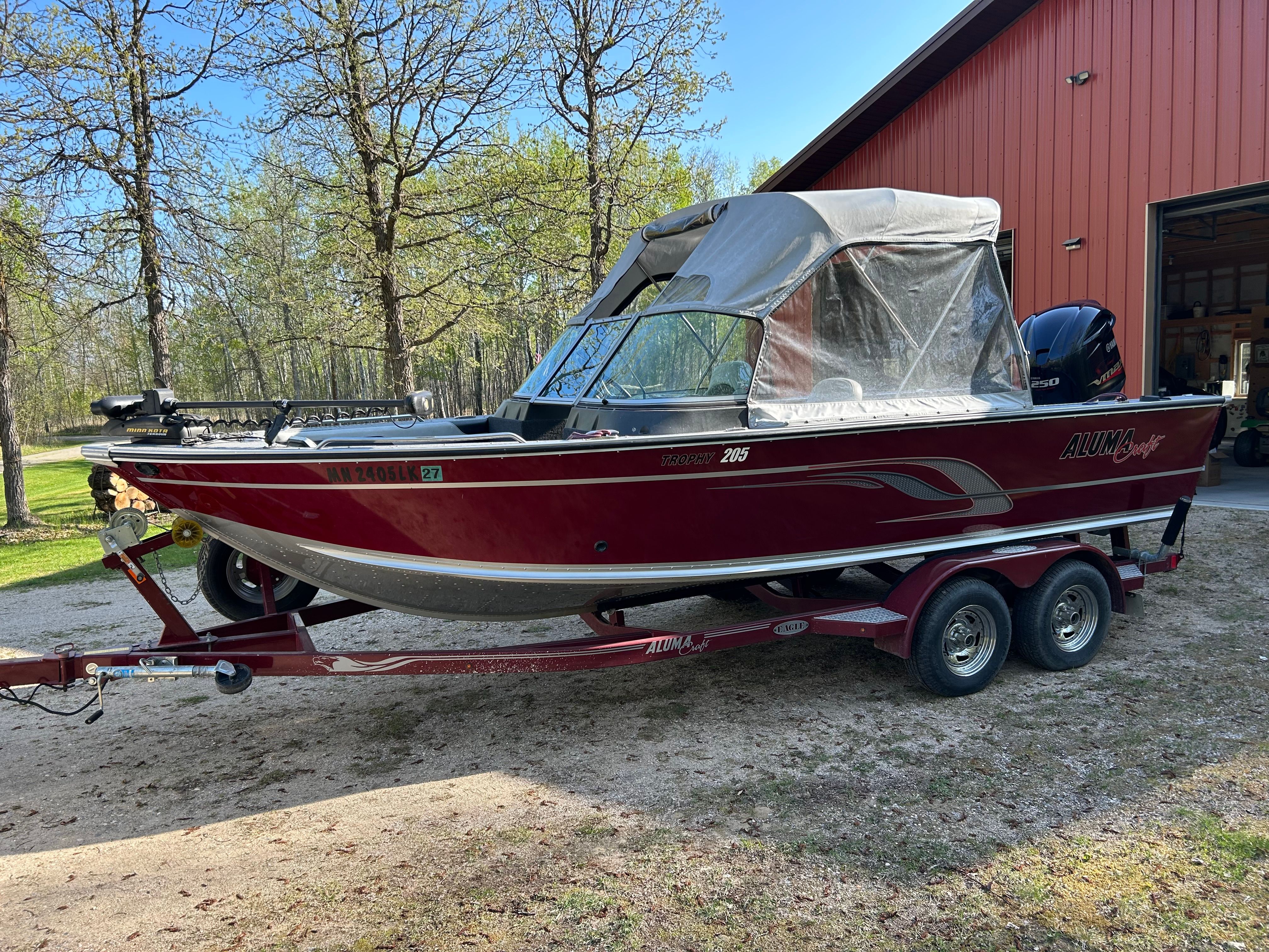 2016 Alumacraft Trophy 205 Sport boat on trailer near red building.
