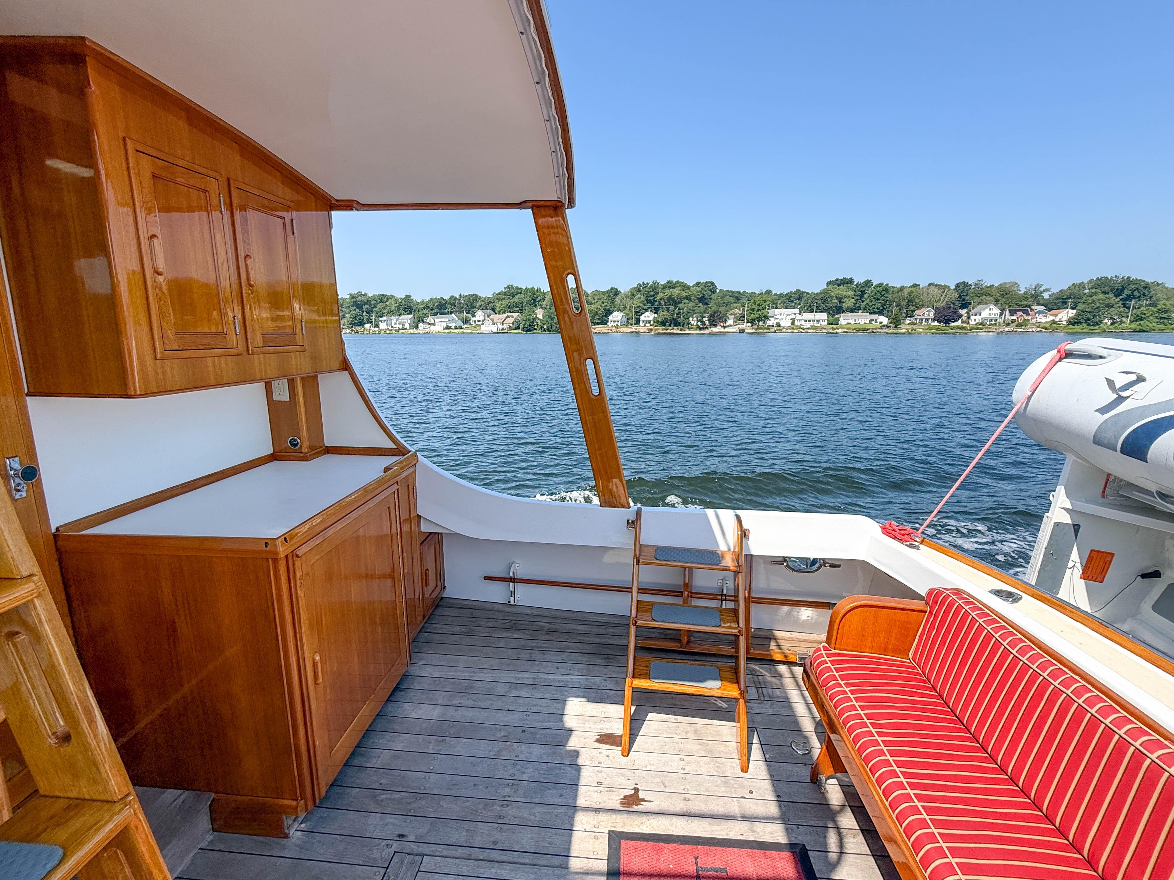 1984 Wilbur 38 boat interior with wooden cabinetry, striped seating, and scenic water view.