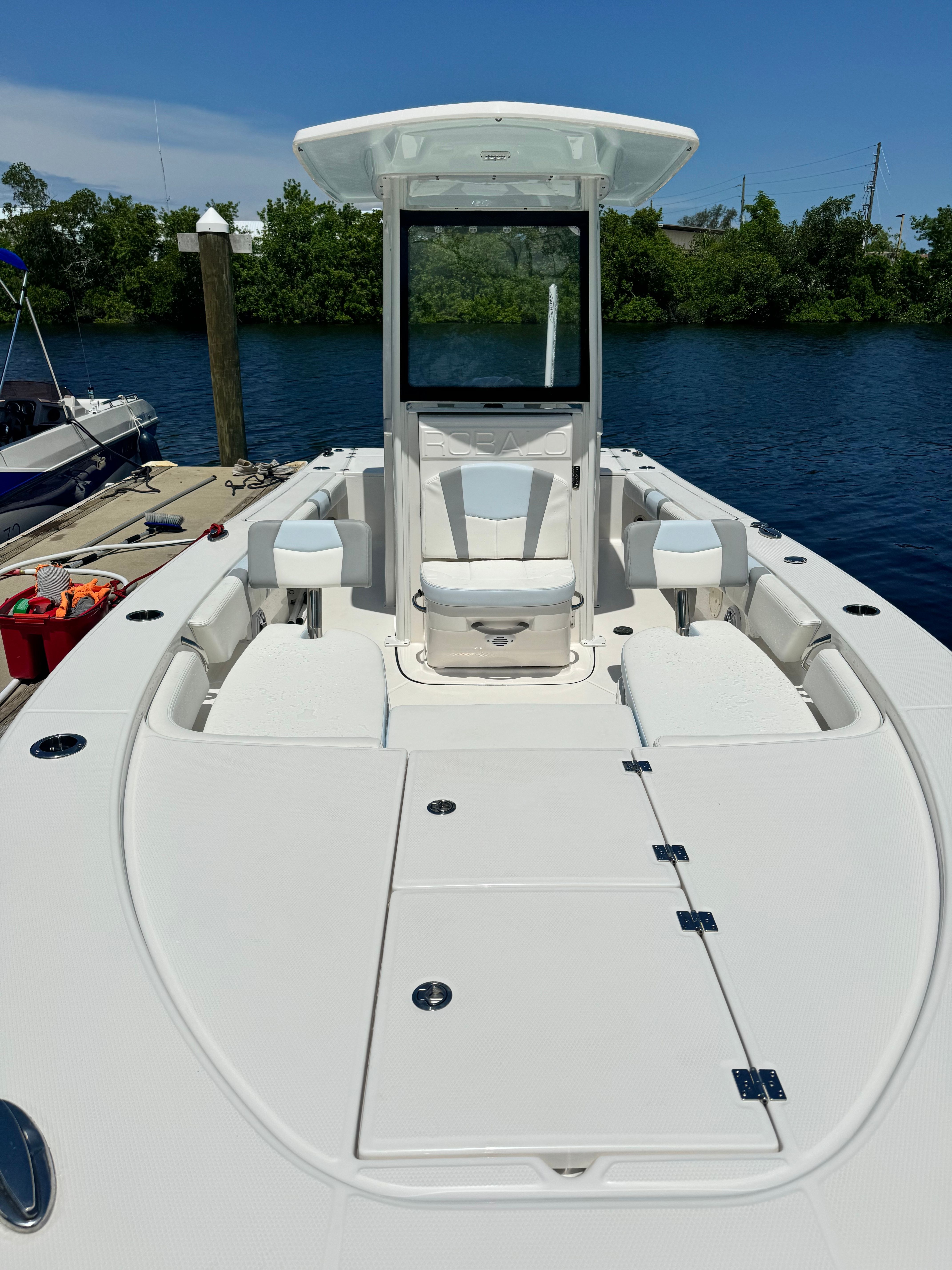 A modern boat with spacious deck and seating, docked by the water.