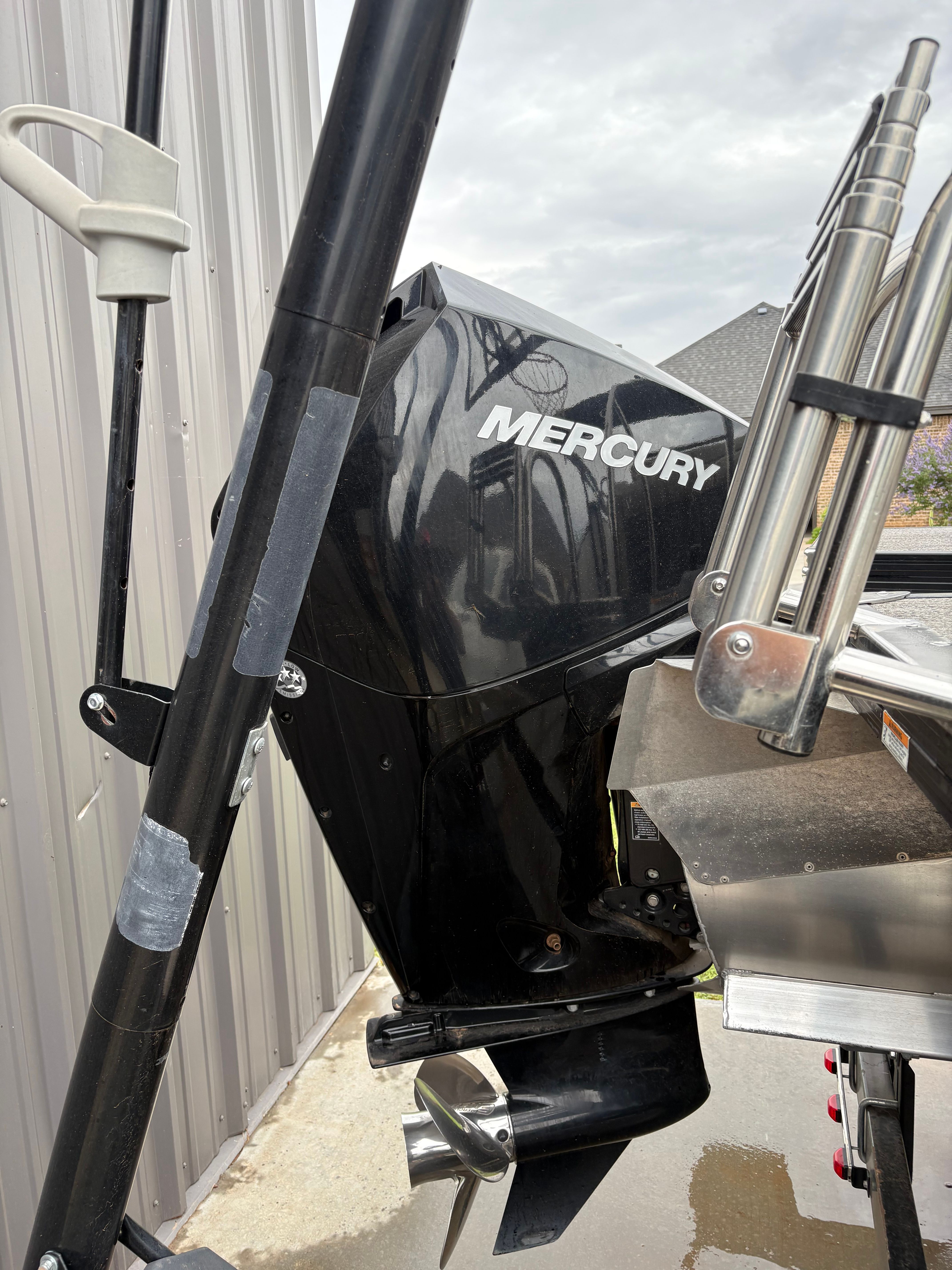 A Mercury outboard motor on a 2021 Barletta C24UC, parked beside a building.