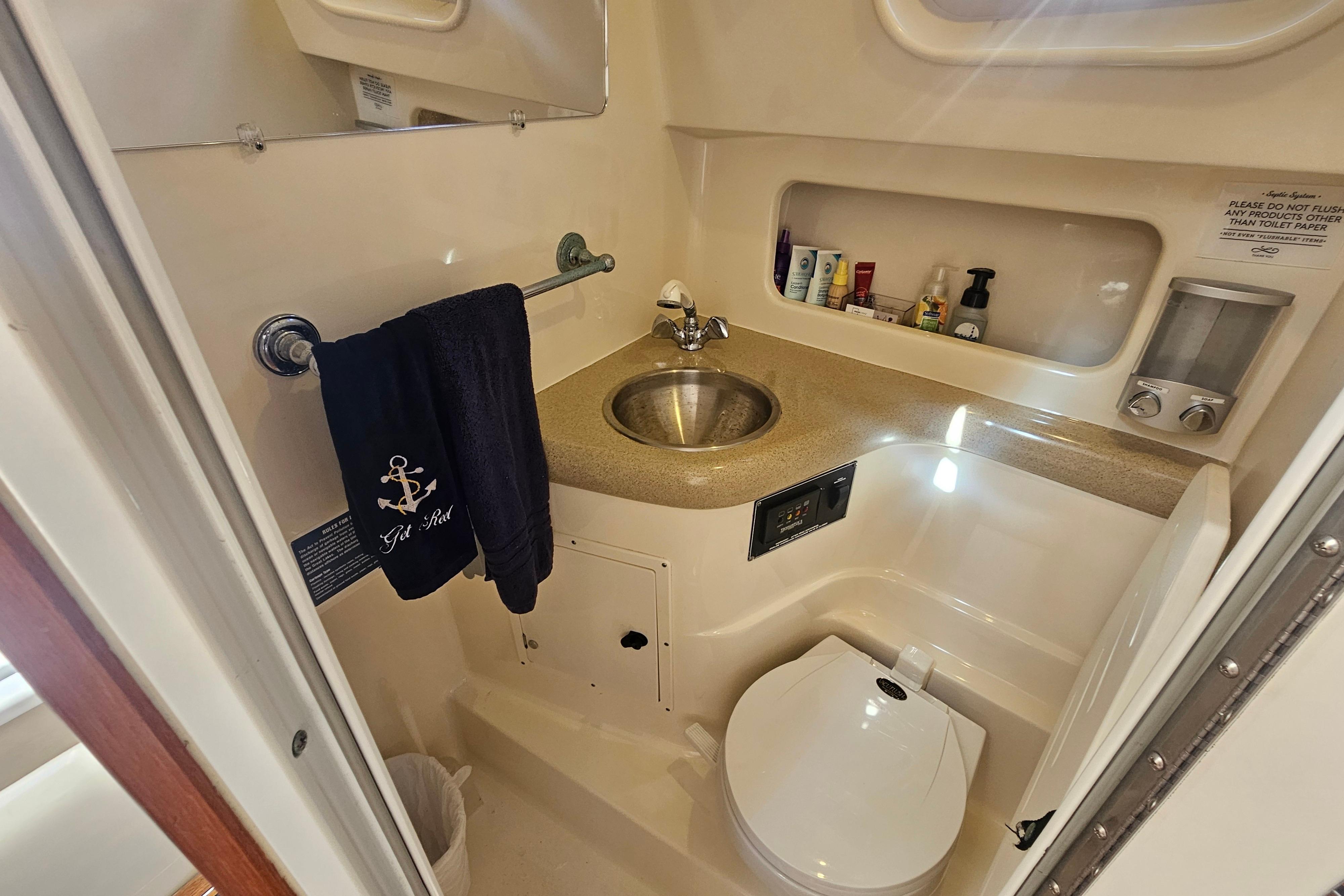2001 Pursuit 3000 Express boat bathroom with sink, toilet, and toiletries.
