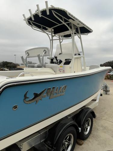 2024 Mako 214 CC boat with blue hull and T-top on trailer.