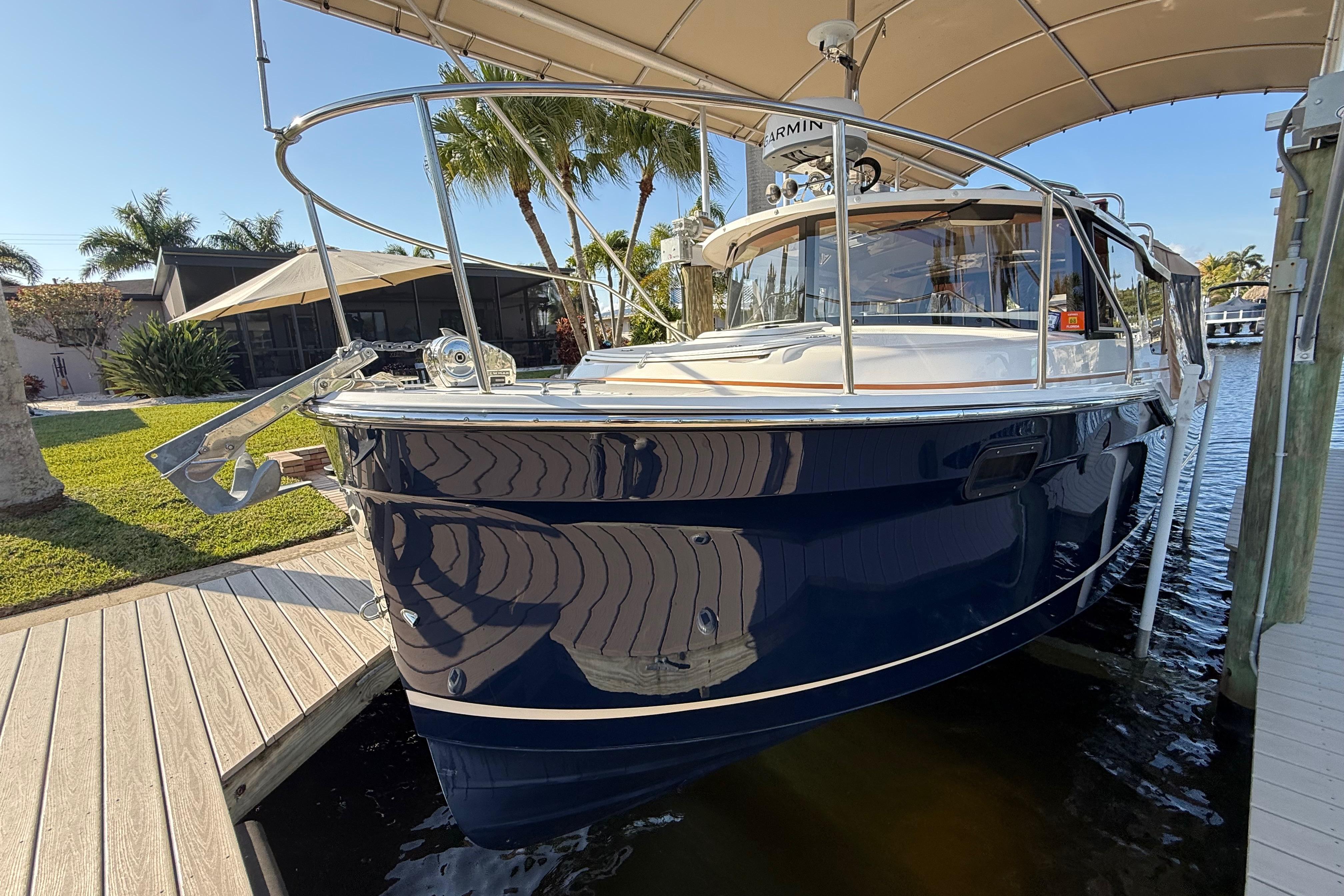 2022 Ranger Tugs R-27 boat docked under canopy, surrounded by tropical scenery.