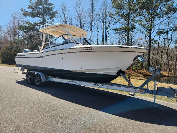 2015 Grady-White Freedom 275 boat on trailer, parked outdoors, surrounded by trees.