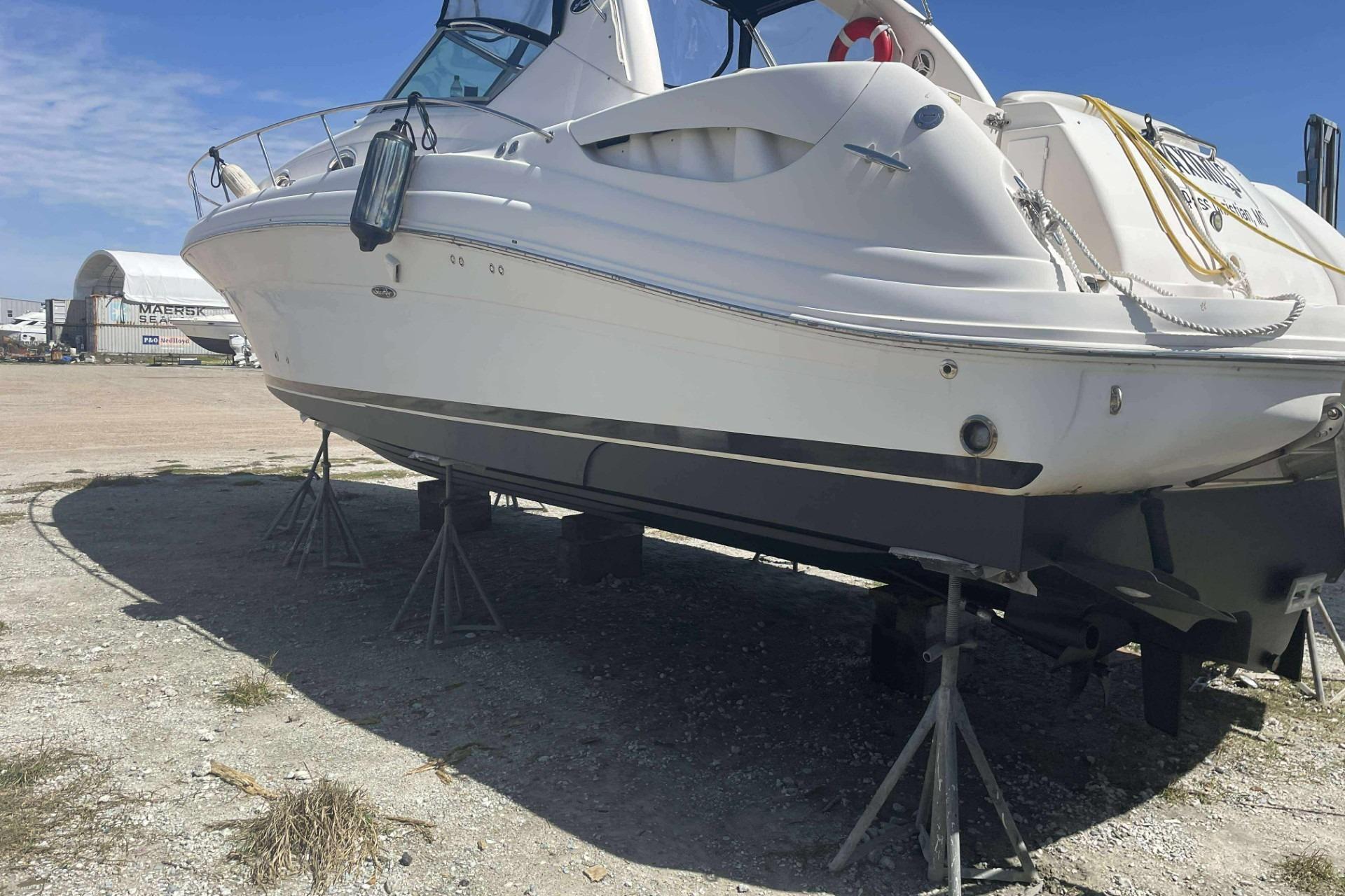 2005 Sea Ray 340 Sundancer yacht on stands, outdoor storage, clear sky background.