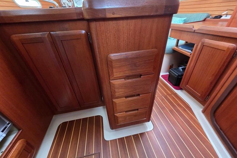 Wooden interior of a 1996 Hunter 336 sailboat, featuring cabinets and drawers.