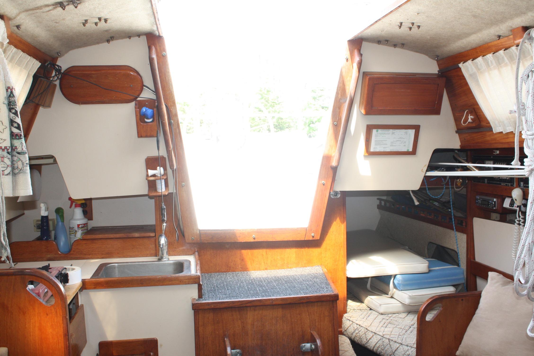 Interior of a 1981 S2 9.2A sailboat featuring a compact kitchen and cozy seating area.