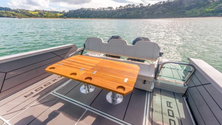2025 Saxdor 320 GTC boat with wooden table, scenic water view.