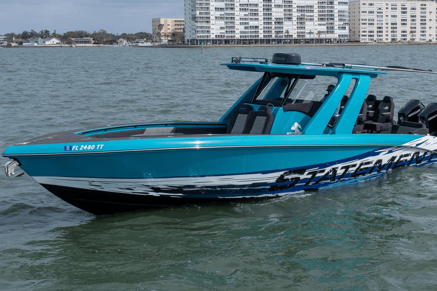 2024 Statement 38 Open boat on water, vibrant blue design, cityscape background.