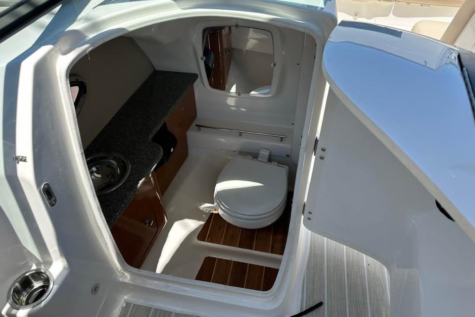 Interior of 2012 Chaparral 284 Sunesta boat featuring a compact bathroom.