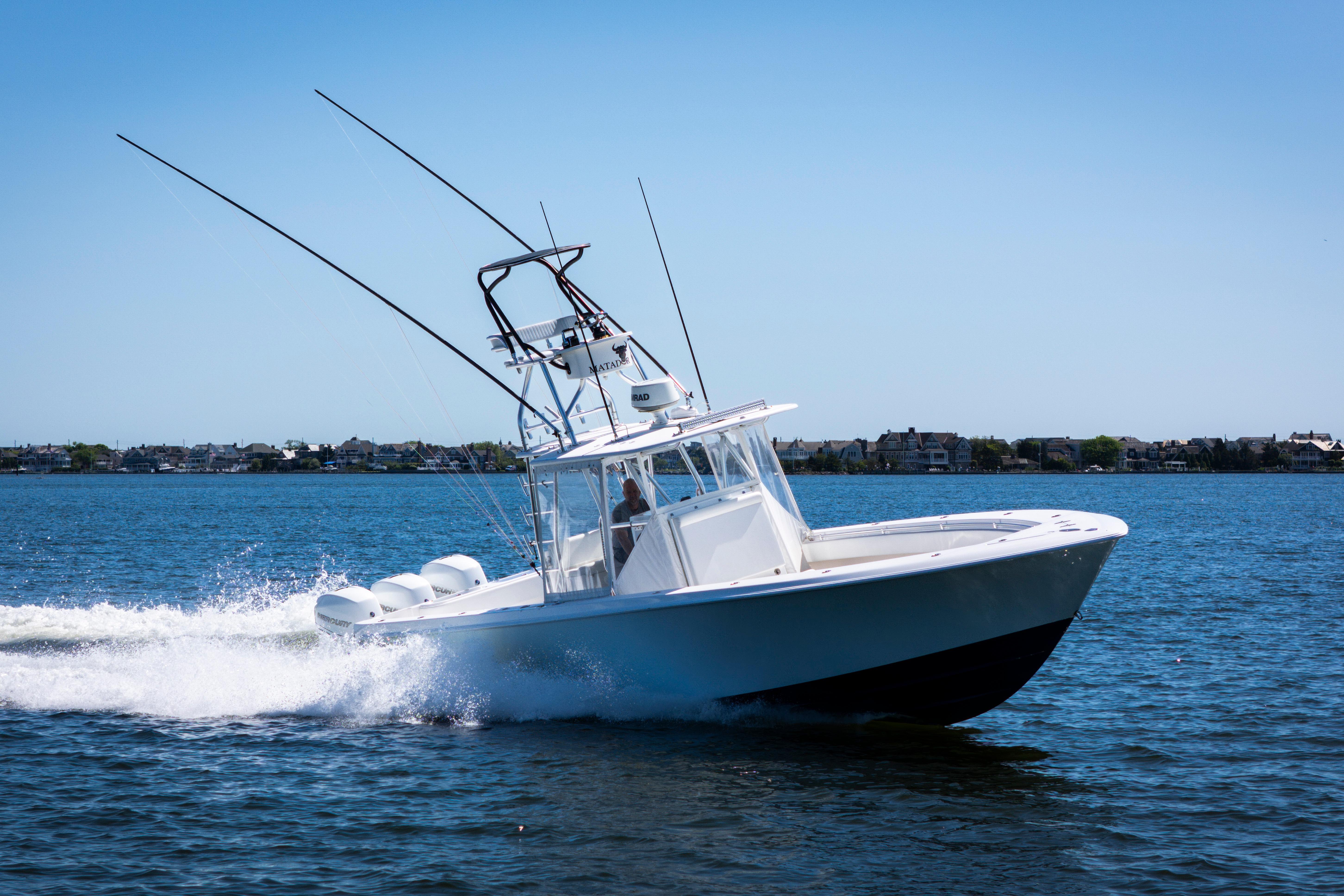 2015 Contender 39 ST boat cruising on open water under clear blue sky.