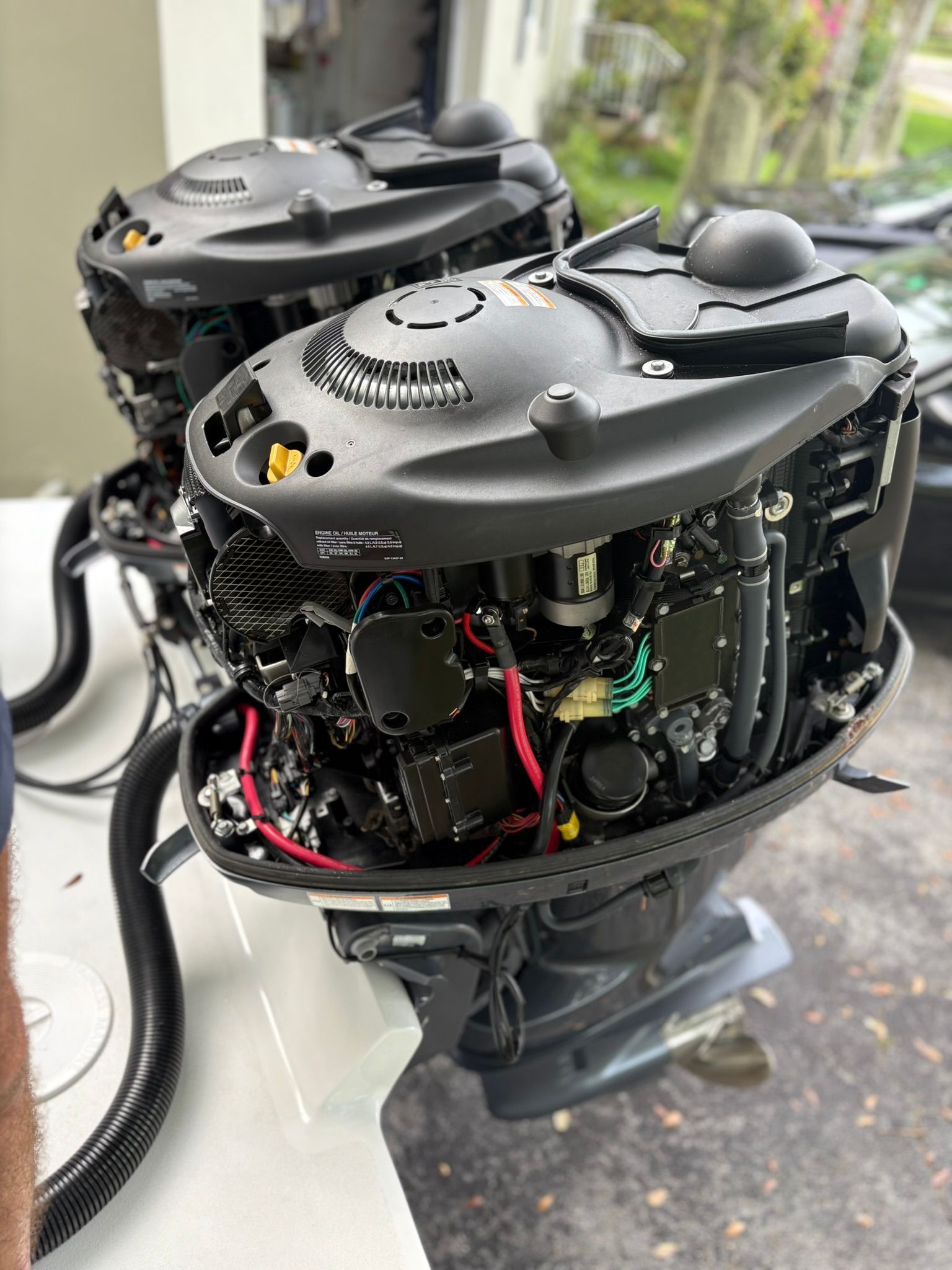 Two outboard motors with exposed components and wiring mounted on a boat.