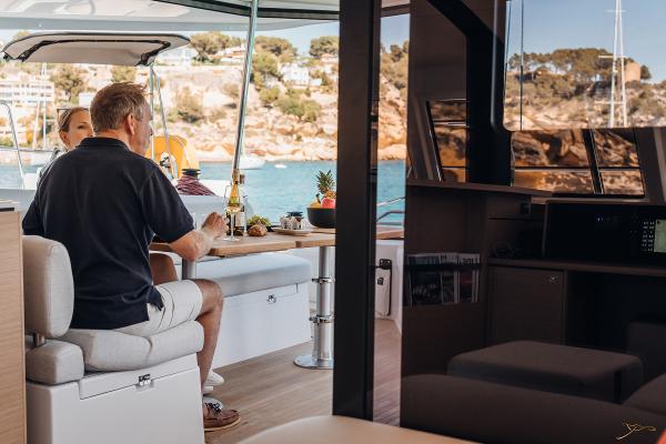 Couple dining on Nautitech 44 Open yacht, 2025 model, with scenic coastal view.