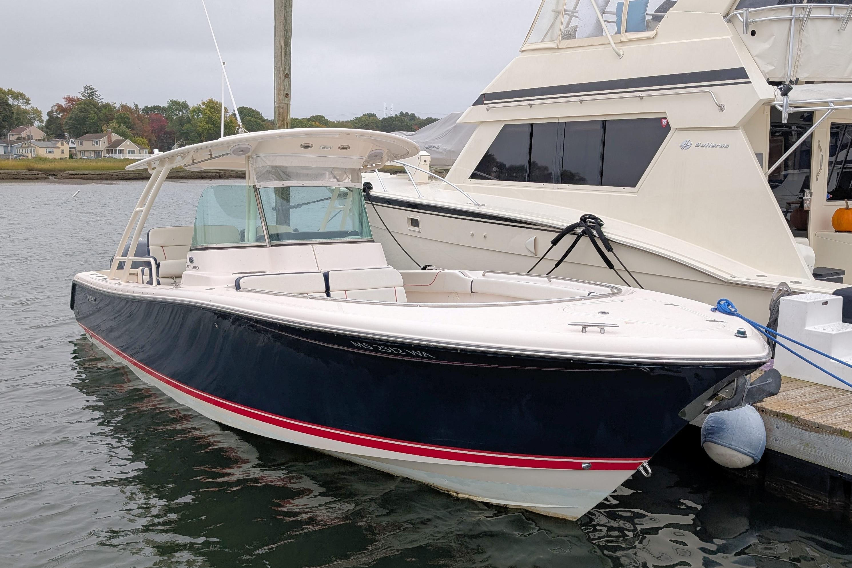 2013 Pursuit ST 310 Sport boat docked in a marina, featuring sleek design and spacious deck.
