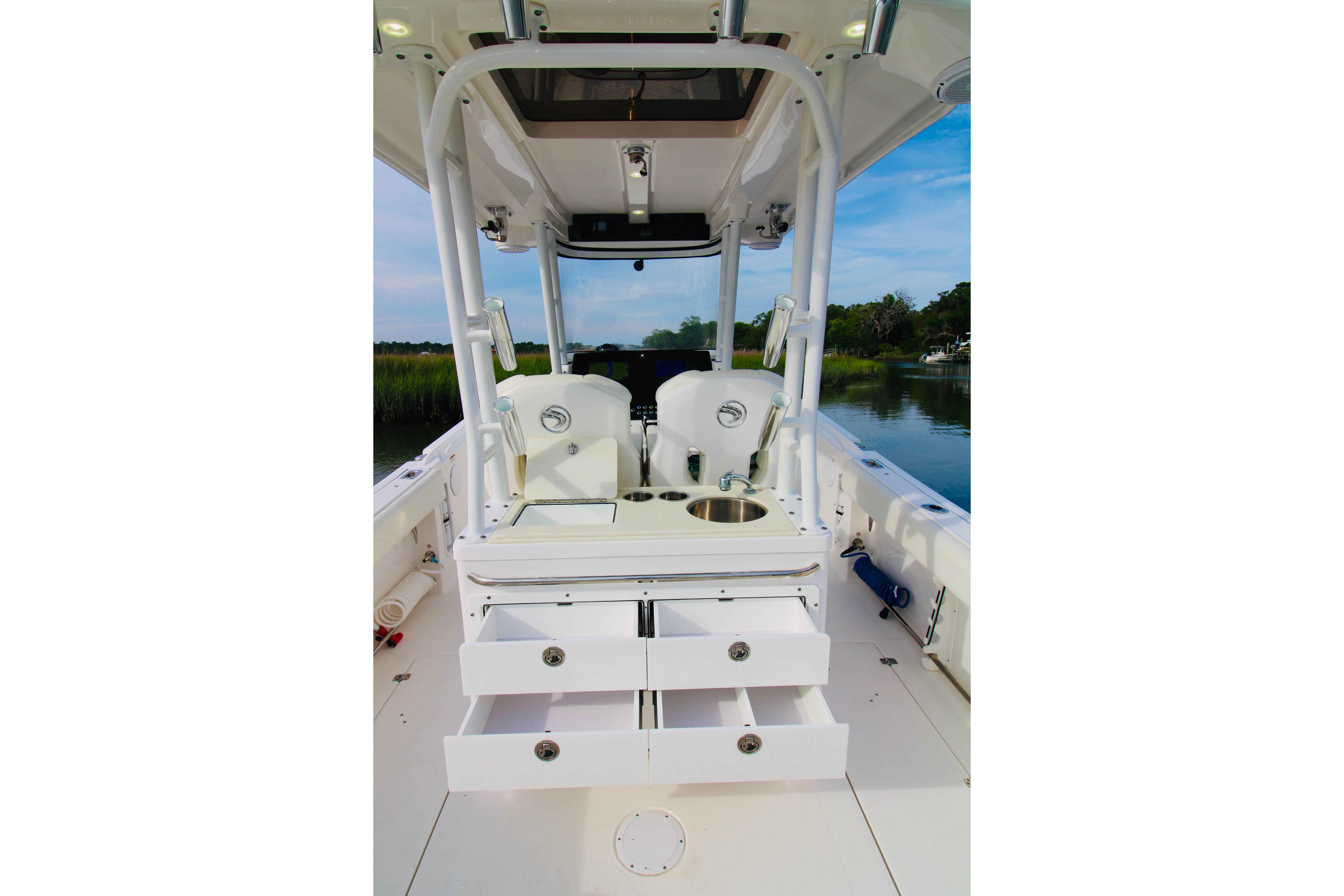 2022 Edgewater 280CC boat interior with seating, storage drawers, and sink, on calm water.