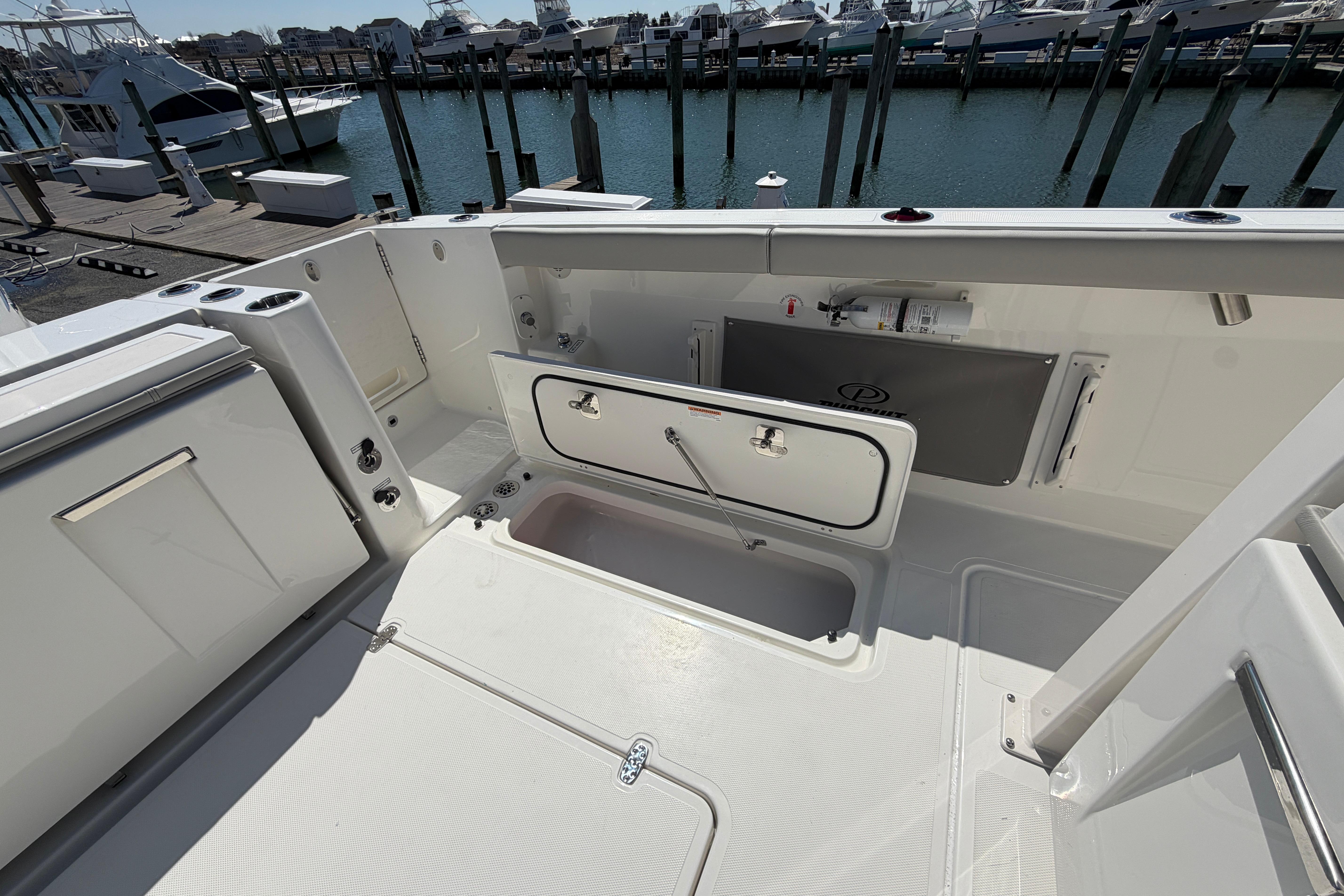 2026 Pursuit S 358 Sport boat deck with storage compartments at marina.