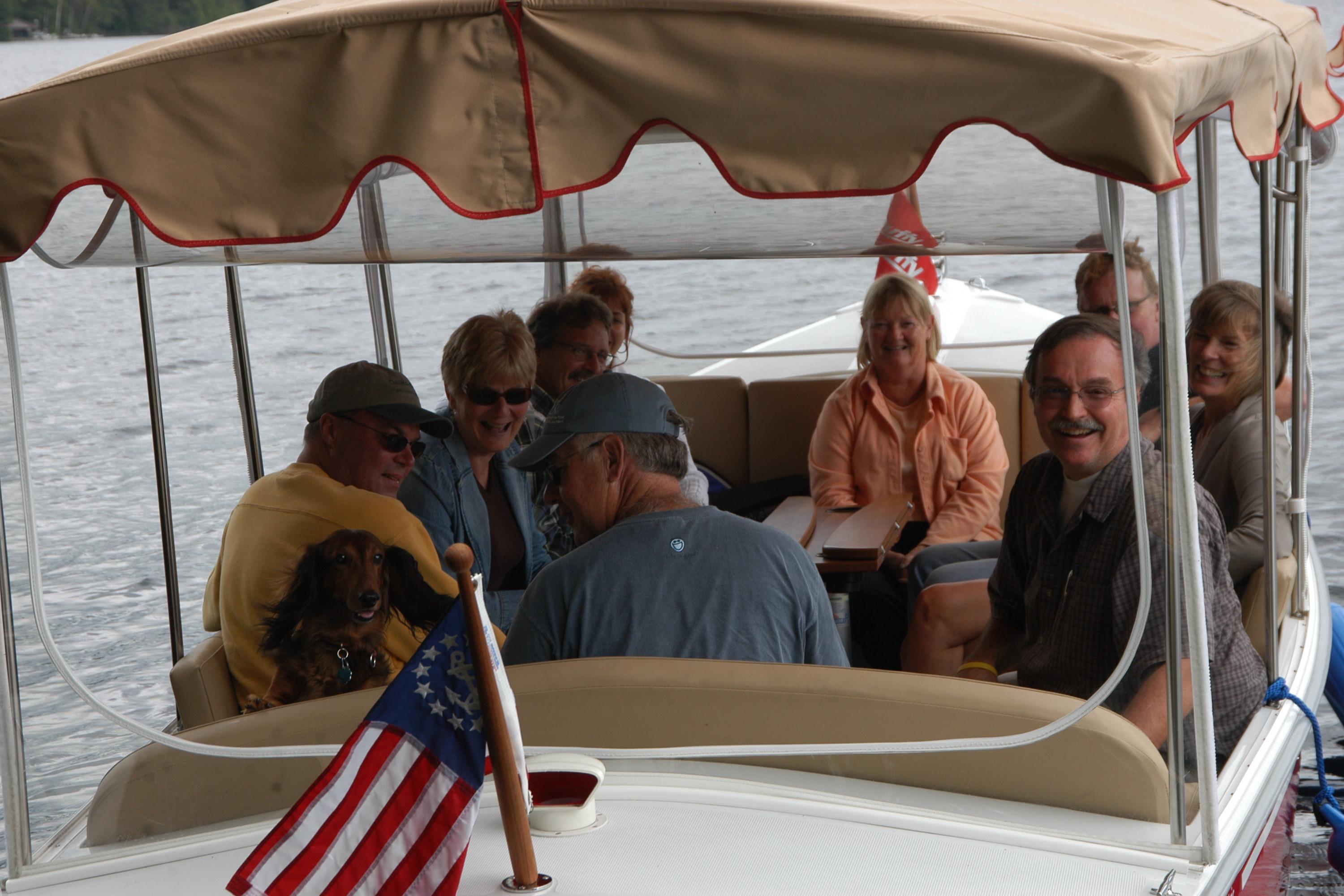 Group enjoying a boat ride on a 2004 Duffy 21 Classic with a dog and American flag.