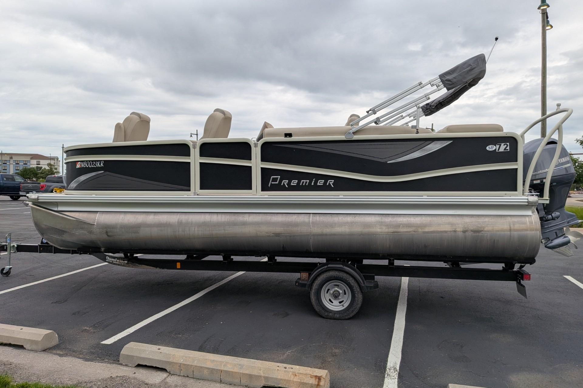 2018 Premier 220 SunSation pontoon boat on trailer in parking lot.