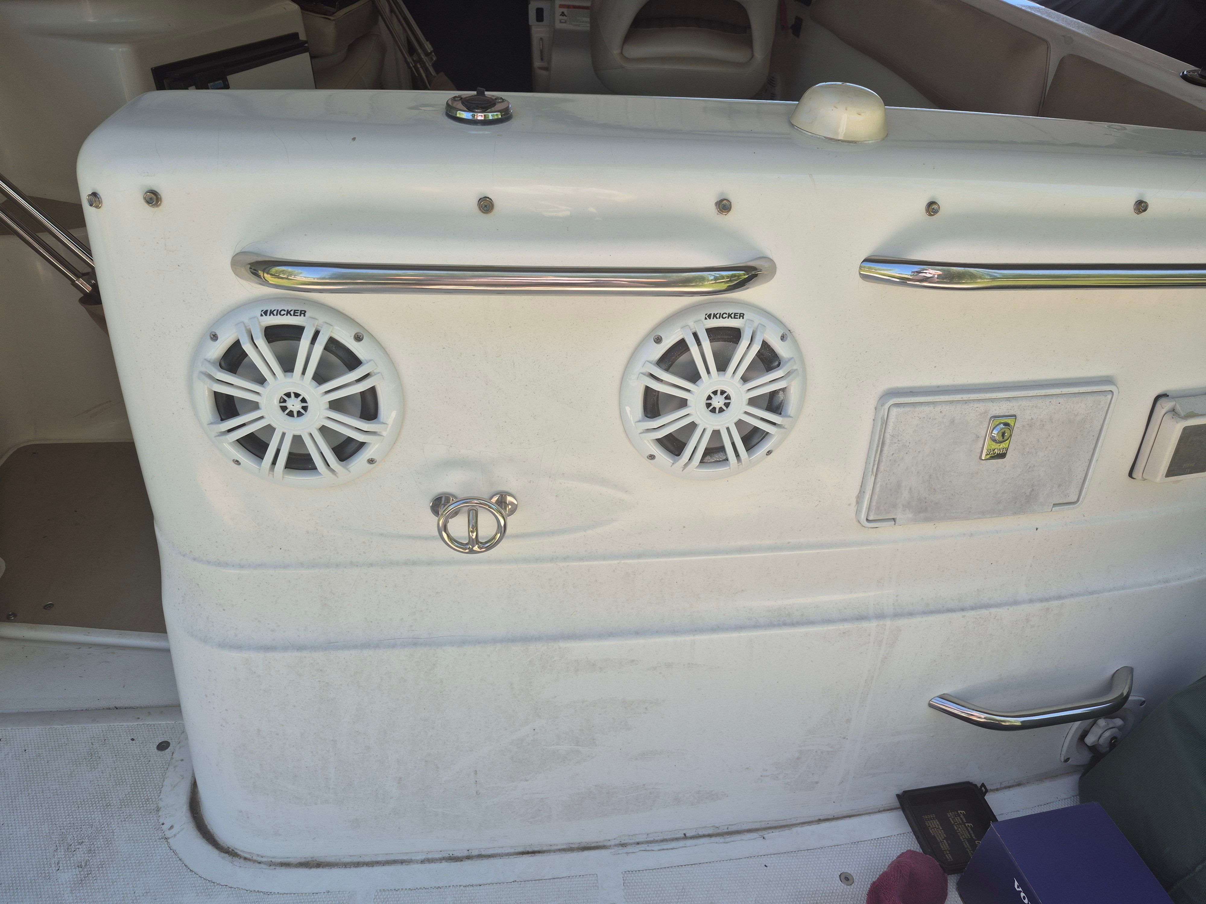 The image shows a boat cockpit with speakers and a handrail.