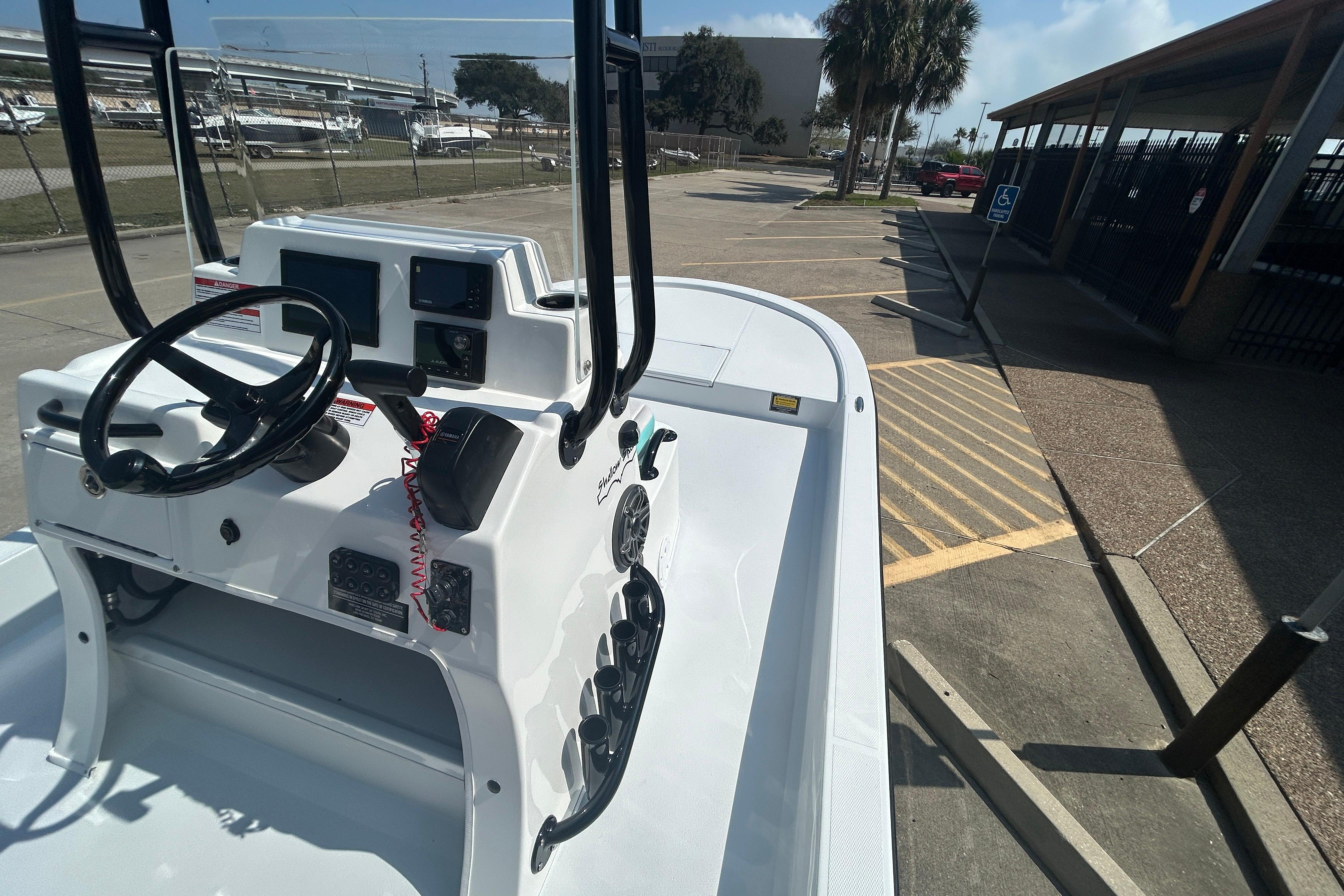 2026 Shallow Sport 18 Sport boat console with steering wheel and controls in a parking area.