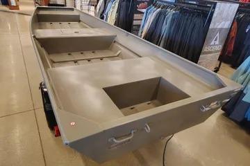 2026 Tracker Grizzly 15 Jon boat displayed indoors, surrounded by clothing racks.