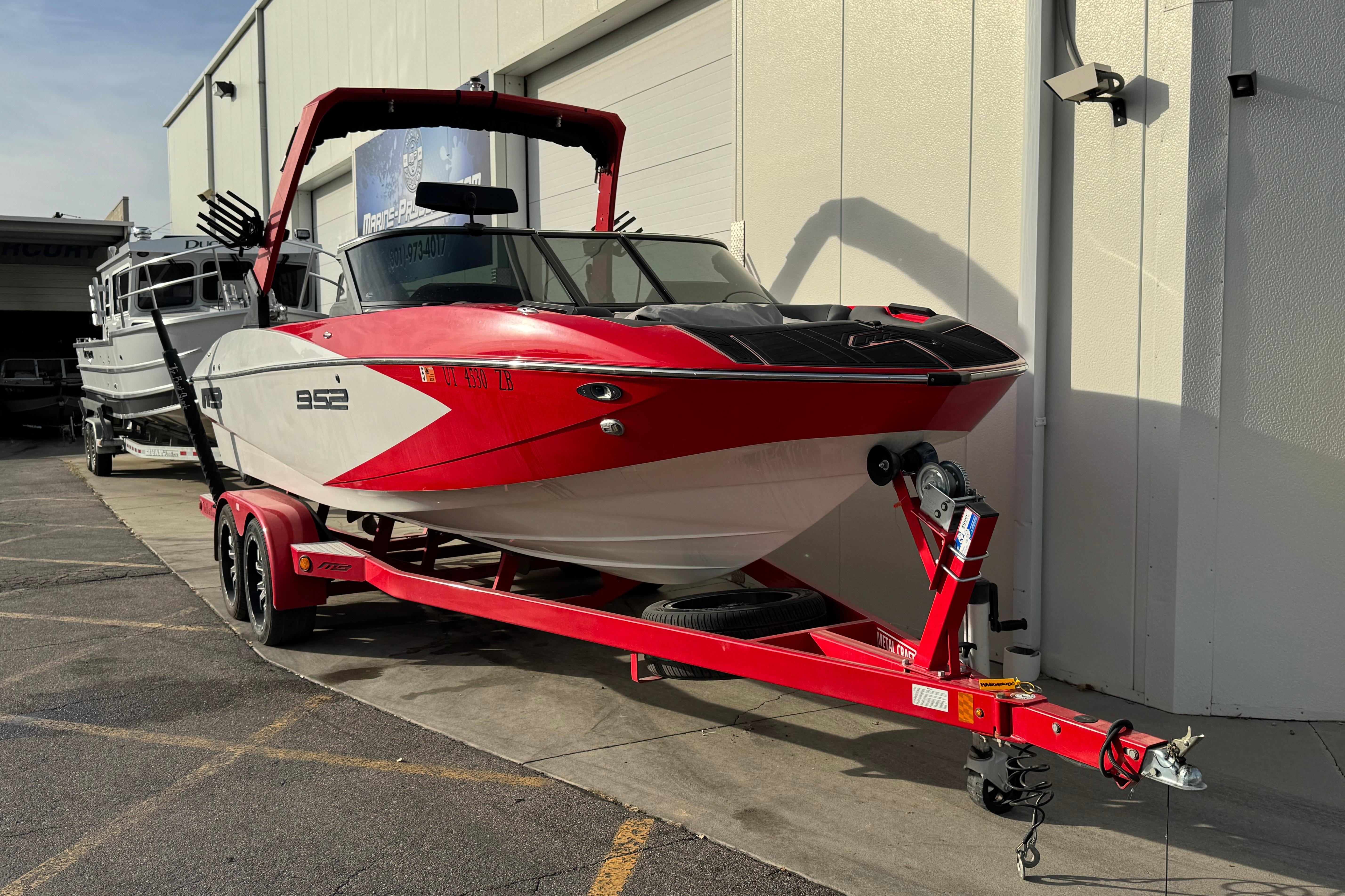 Red and white 2020 MB B52 23 Classic boat on trailer, parked outside.