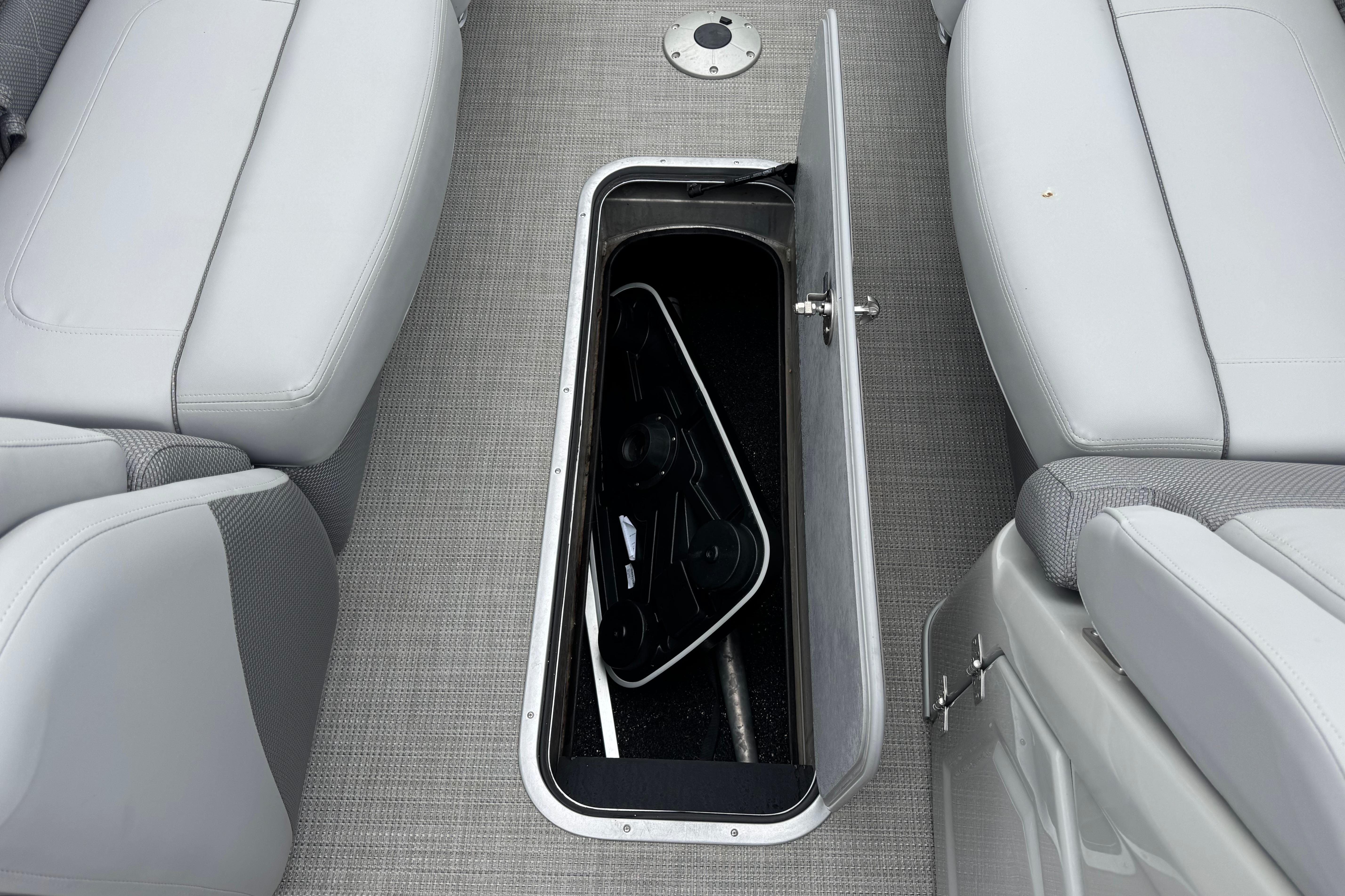 2023 Regency 250 LE3 boat interior storage compartment with open hatch and seating.