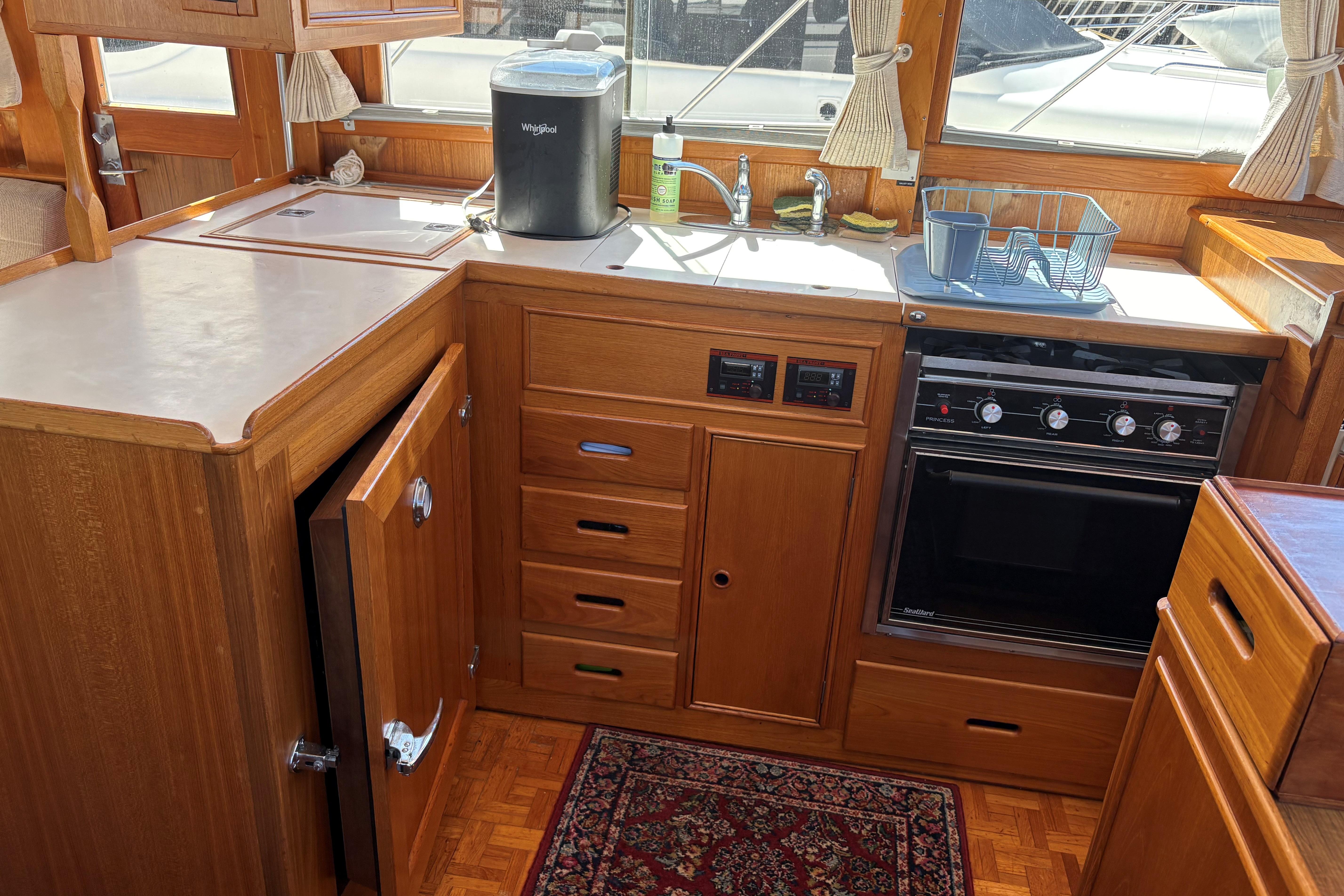 1990 Grand Banks Classic yacht kitchen with wood cabinetry, oven, and sink.