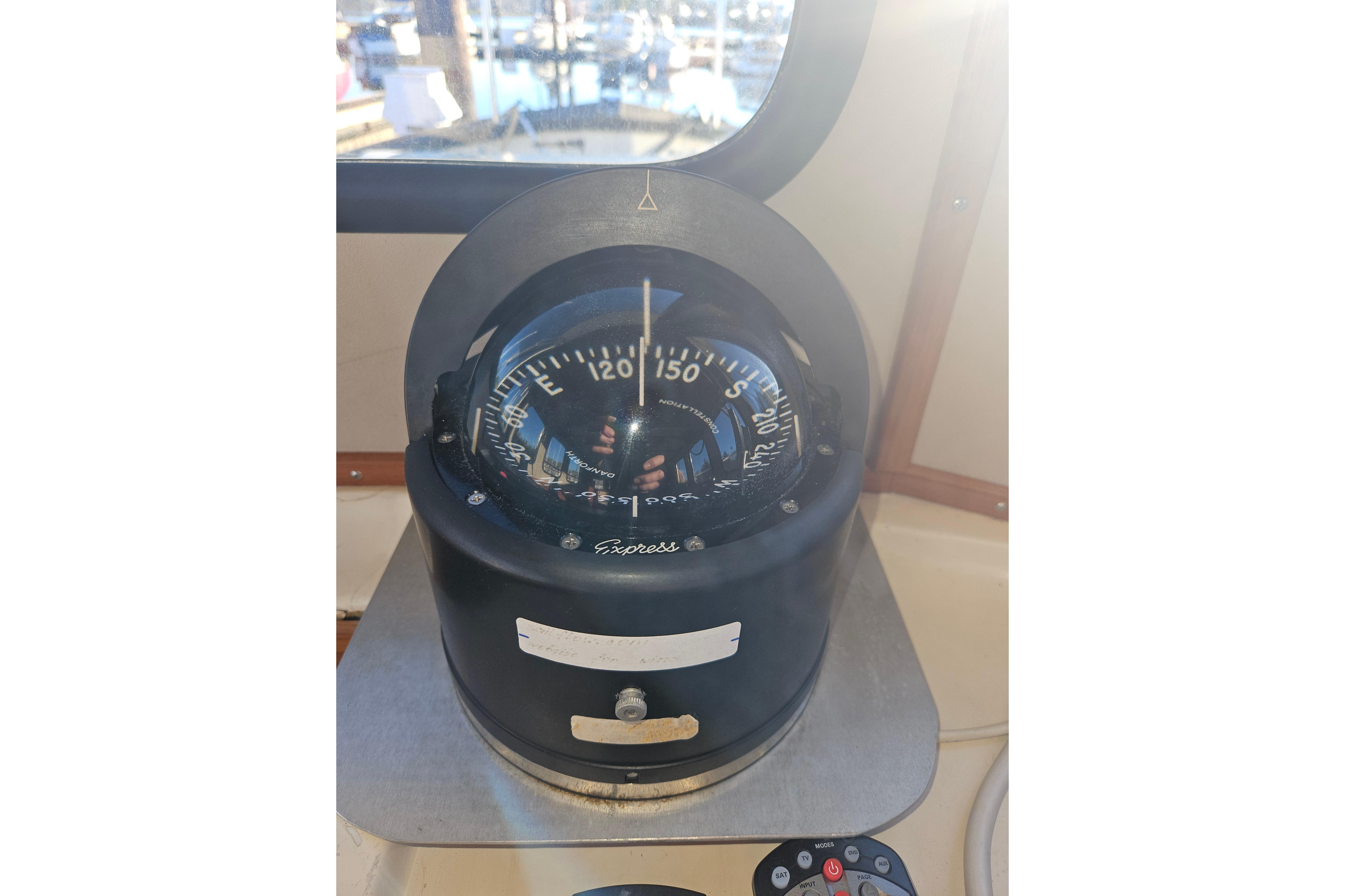 Compass on 1981 Nordic Tug Cricket boat, with marina view through window.