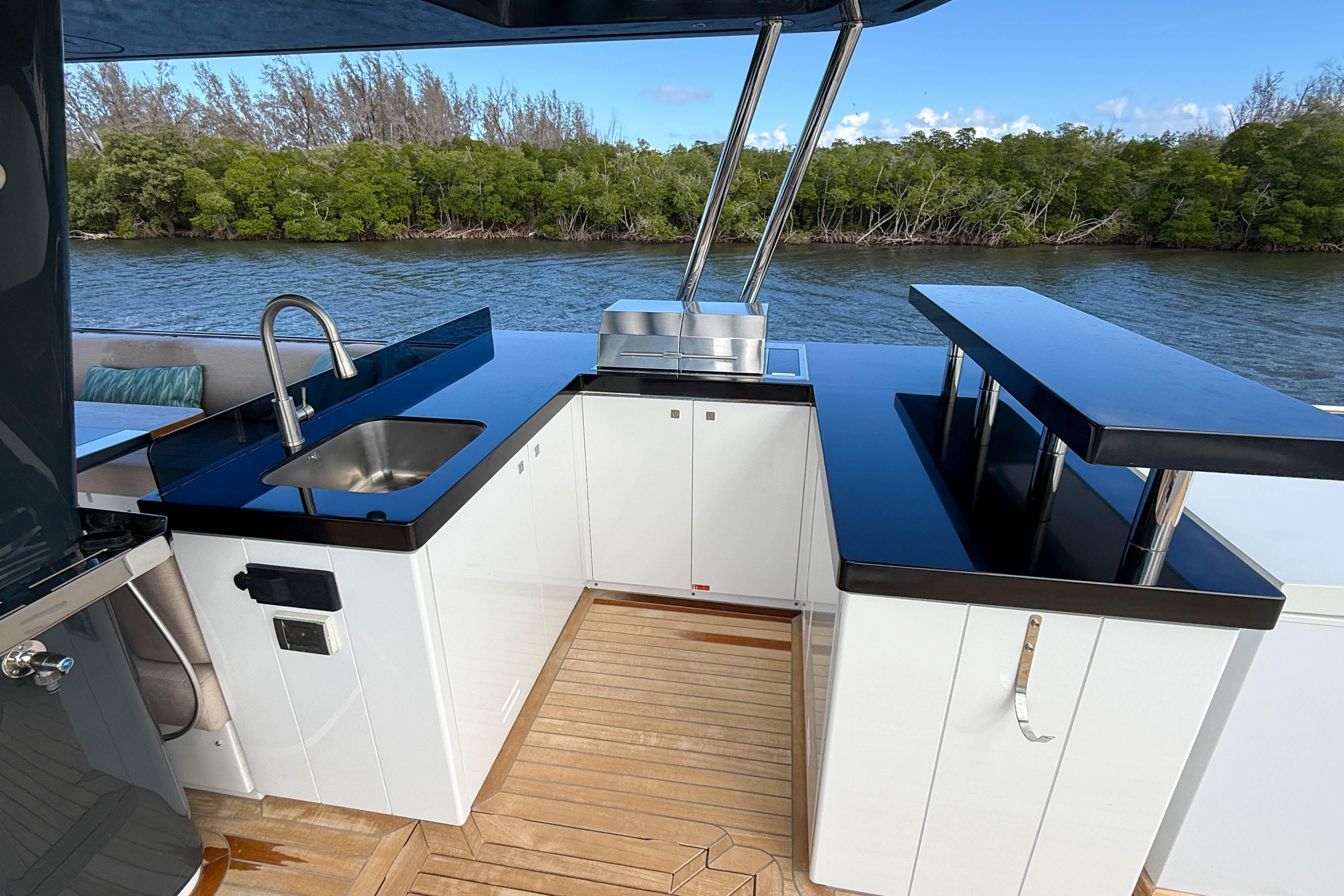 Outdoor kitchen on 2023 Sirena 68 yacht with sink, grill, and bar area.