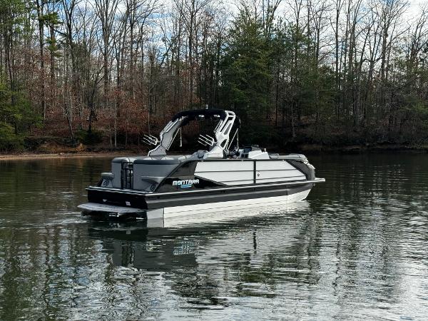 2025 Montara Surf Boss 2.0 25 pontoon boat on a calm lake, surrounded by trees.