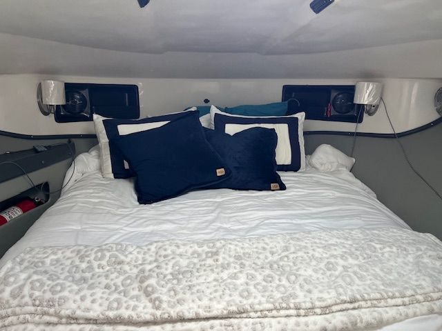 The image shows a cozy cabin with a large bed, surrounded by pillows and blankets.