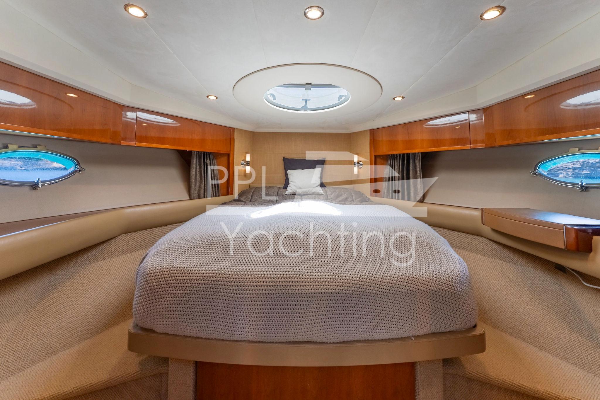 Luxurious 2006 Princess V53 yacht cabin with elegant wood finishes and cozy bedding.