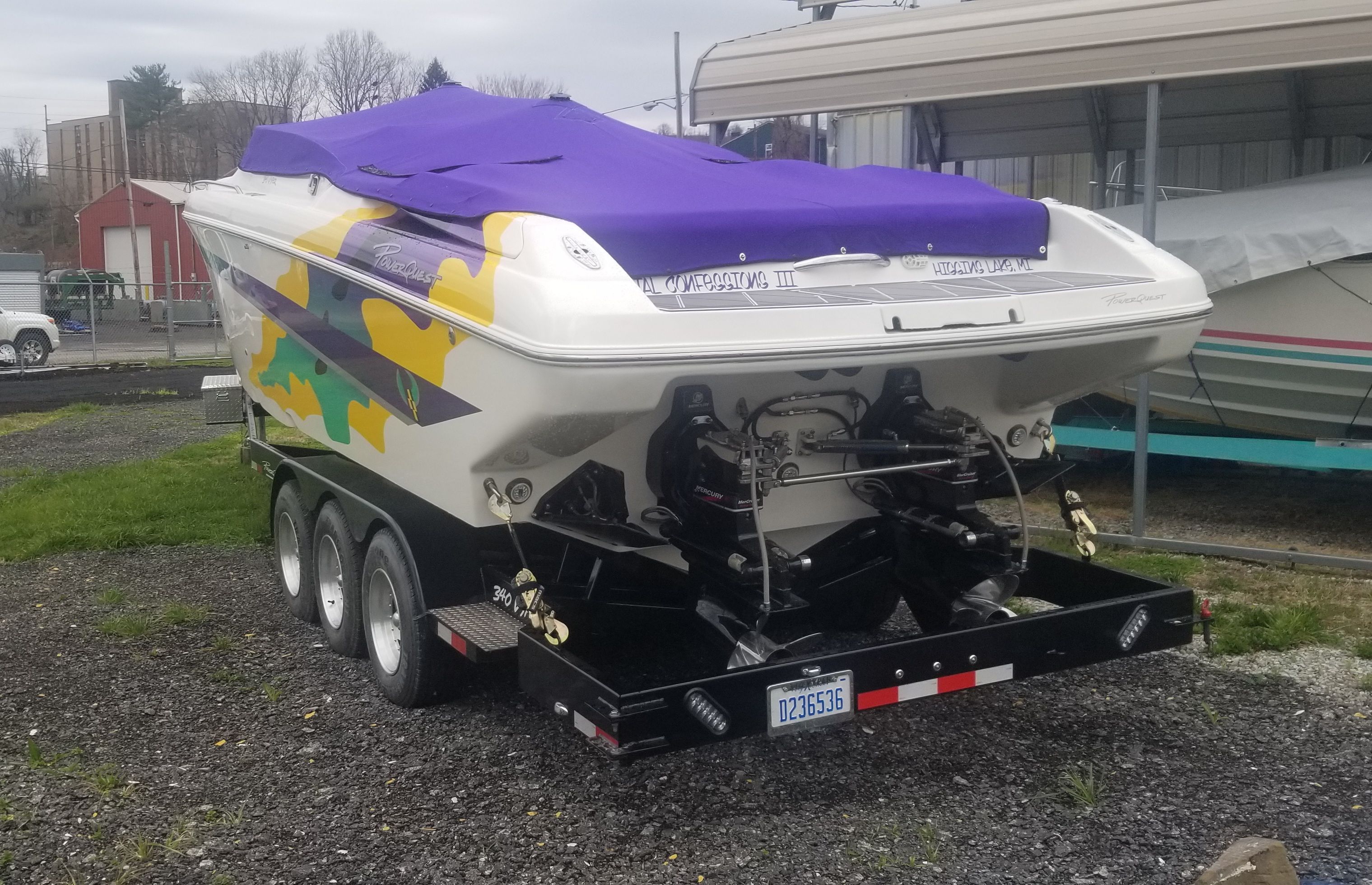 A 2002 Powerquest 340 Vyper boat on a trailer with a purple cover.