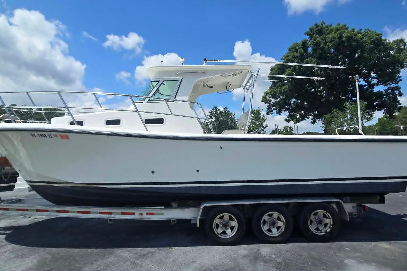 2003 True World Marine 286 boat on trailer under blue sky.
