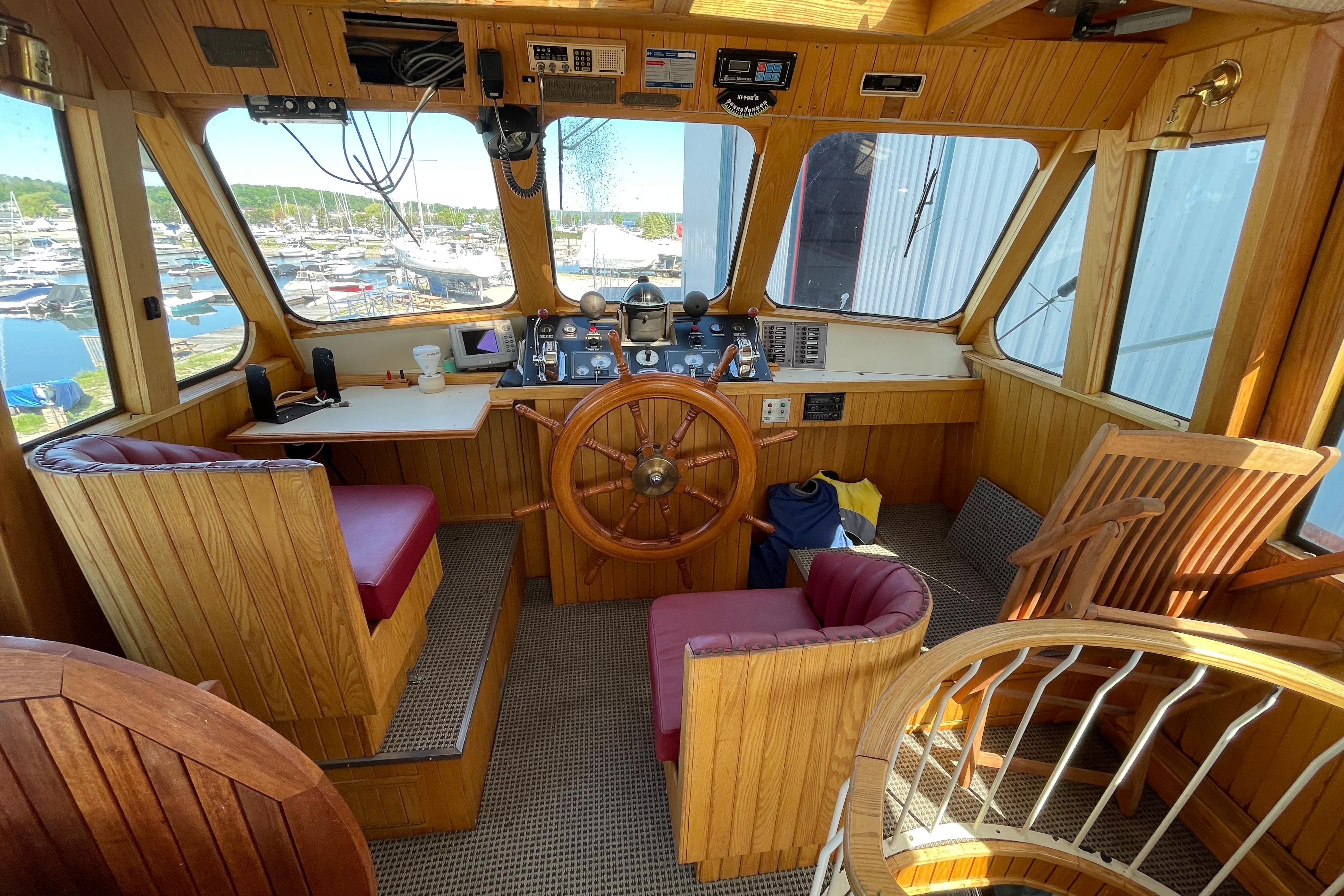 1966 Vinette 430 Trawler helm with wooden interior, steering wheel, and marina view.