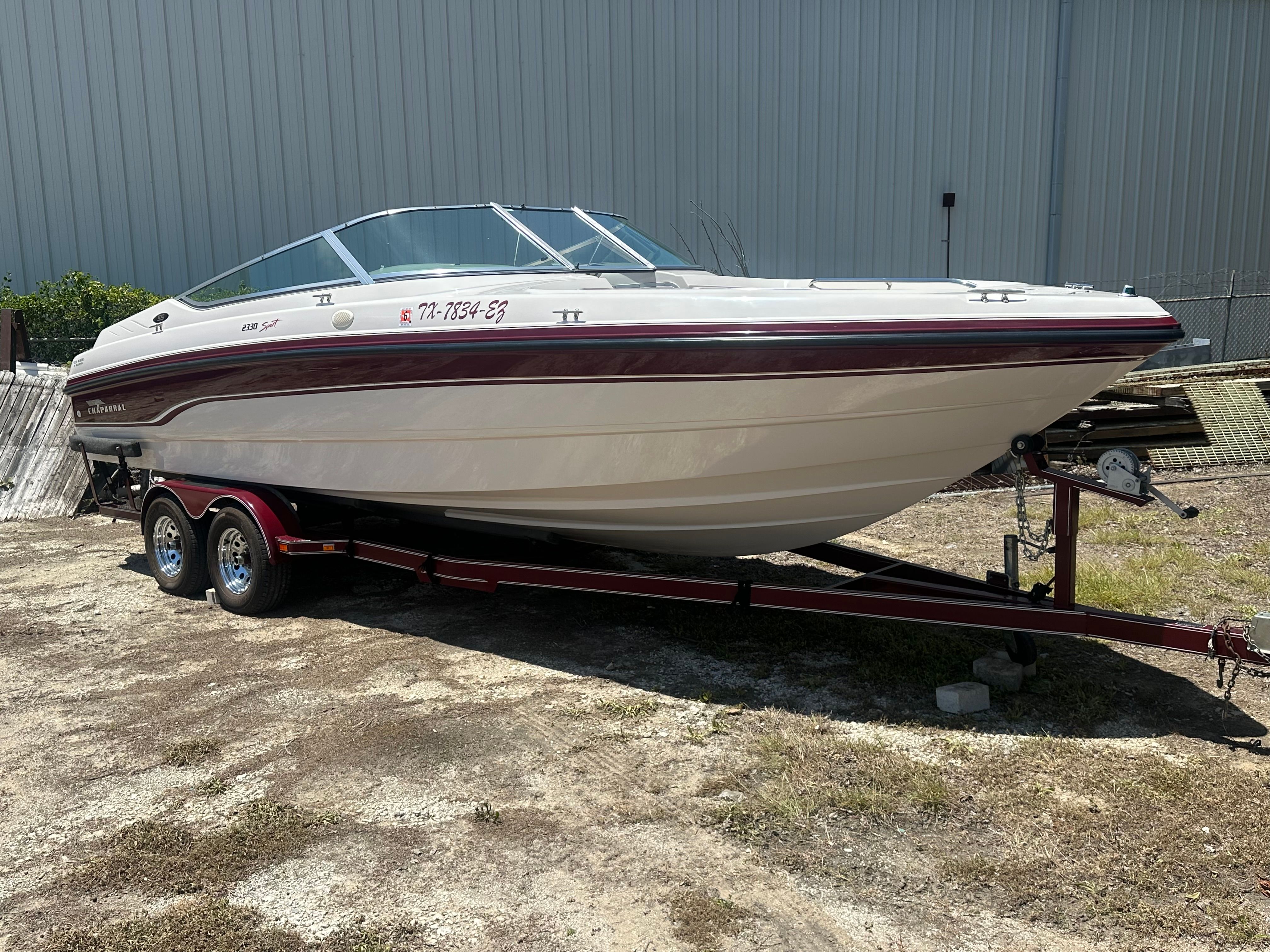 A 1995 Chaparral 2330 boat on a trailer in front of a large building.