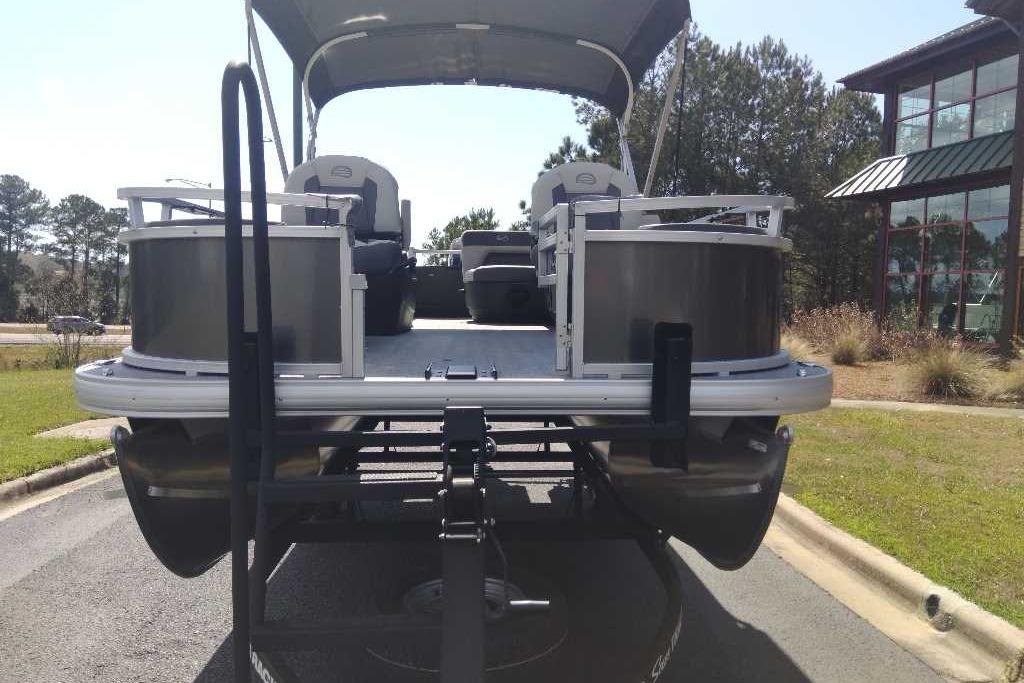 2026 Sun Tracker Bass Buggy 18 DLX pontoon boat on trailer, parked outdoors.