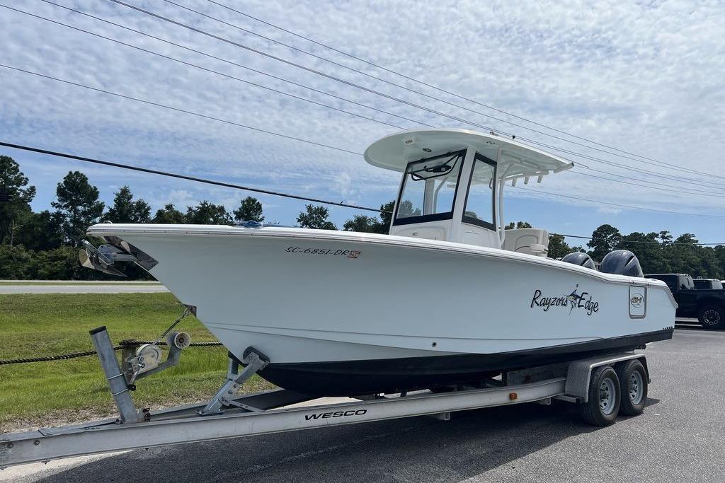 2021 Sea Hunt Gamefish 25 boat on trailer, parked outdoors under a cloudy sky.