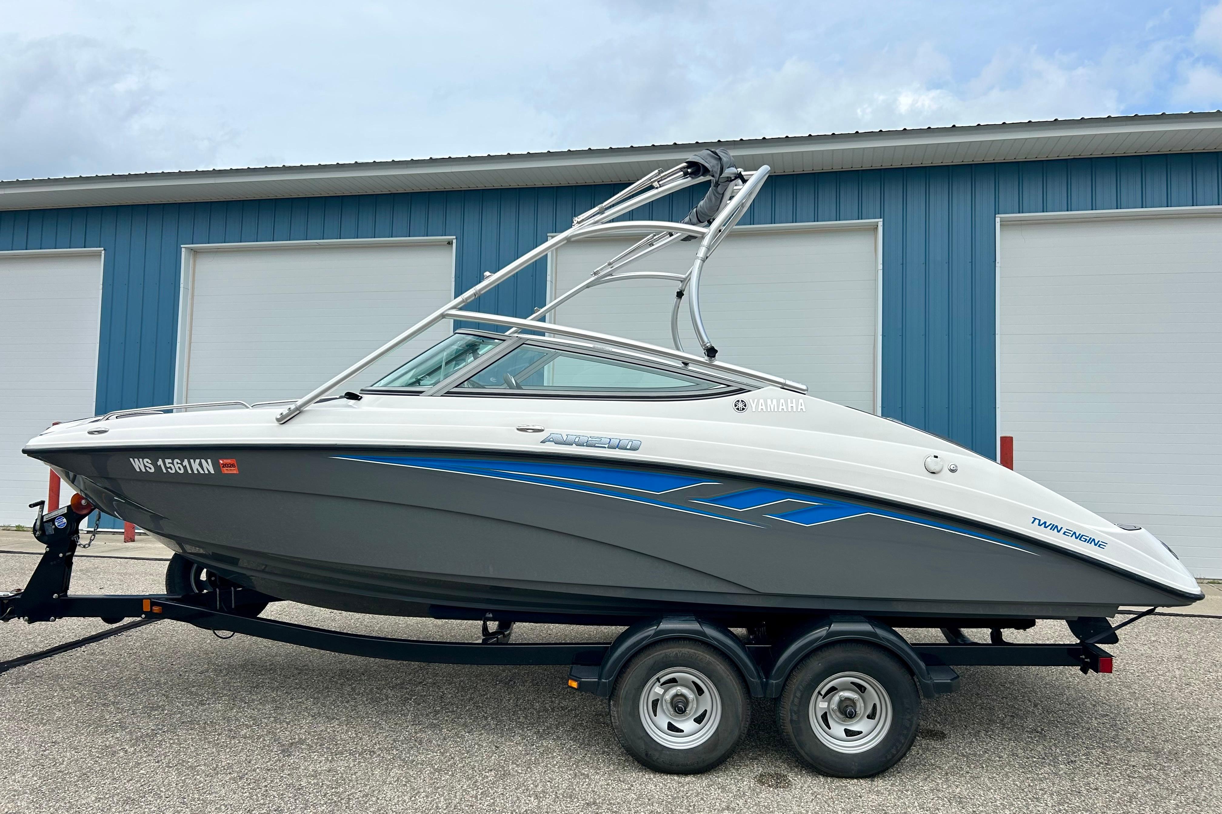 2015 Yamaha Boats AR210 on trailer, parked outside blue warehouse.