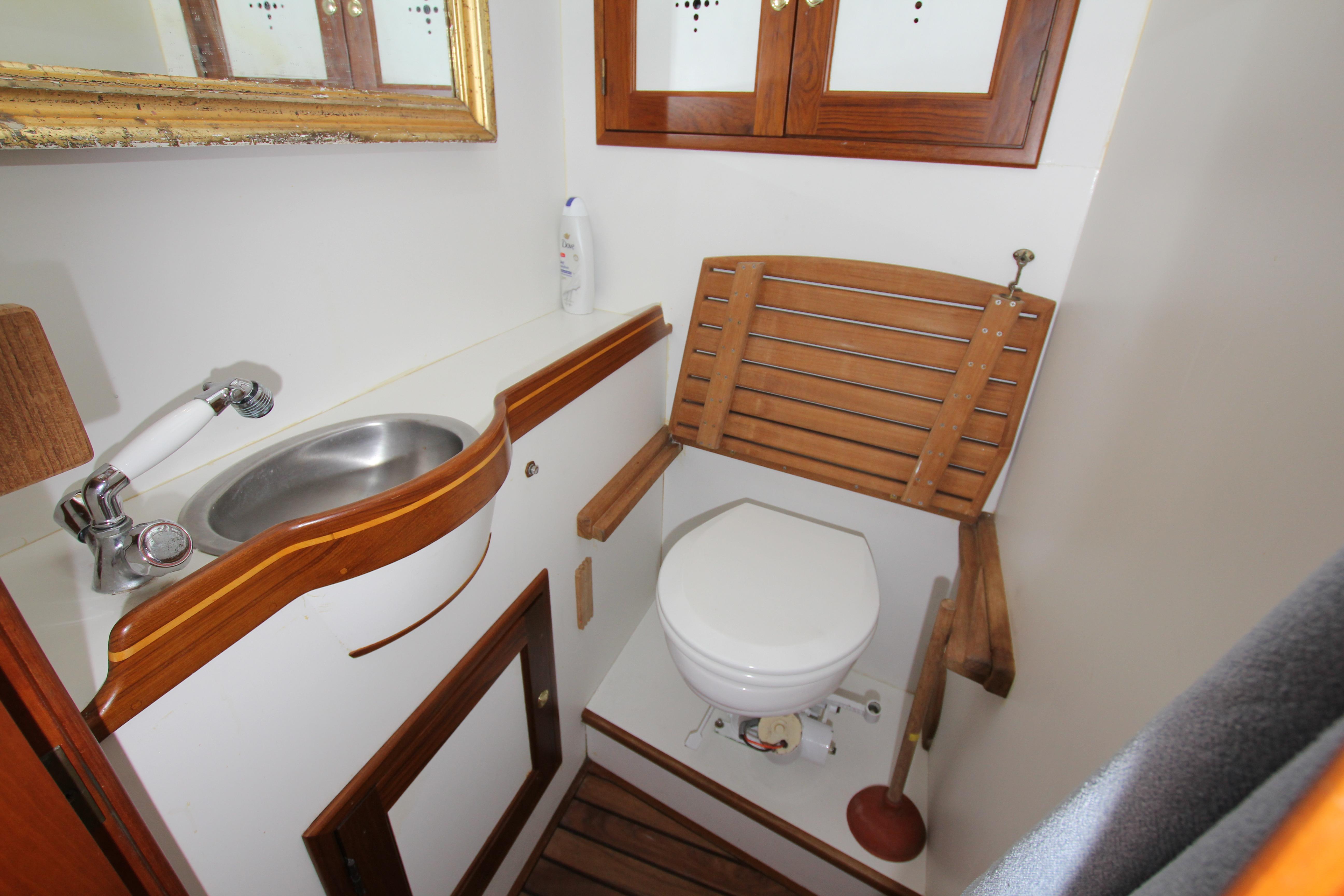 Compact boat bathroom with wooden accents, featuring a sink and toilet. Able Apogee 50, 1998 model.
