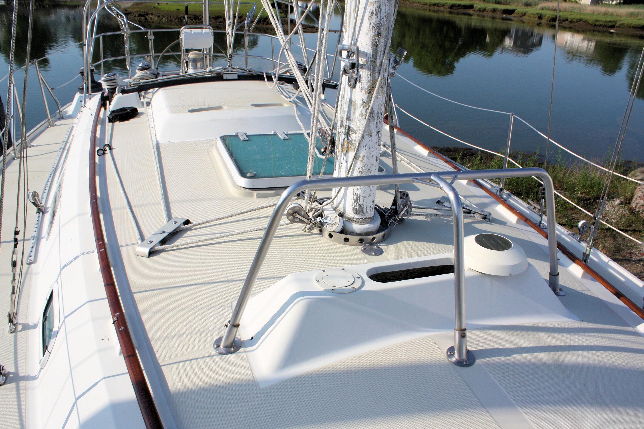1987 Ericson 38-200 sailboat deck with mast and railing, docked by calm water.