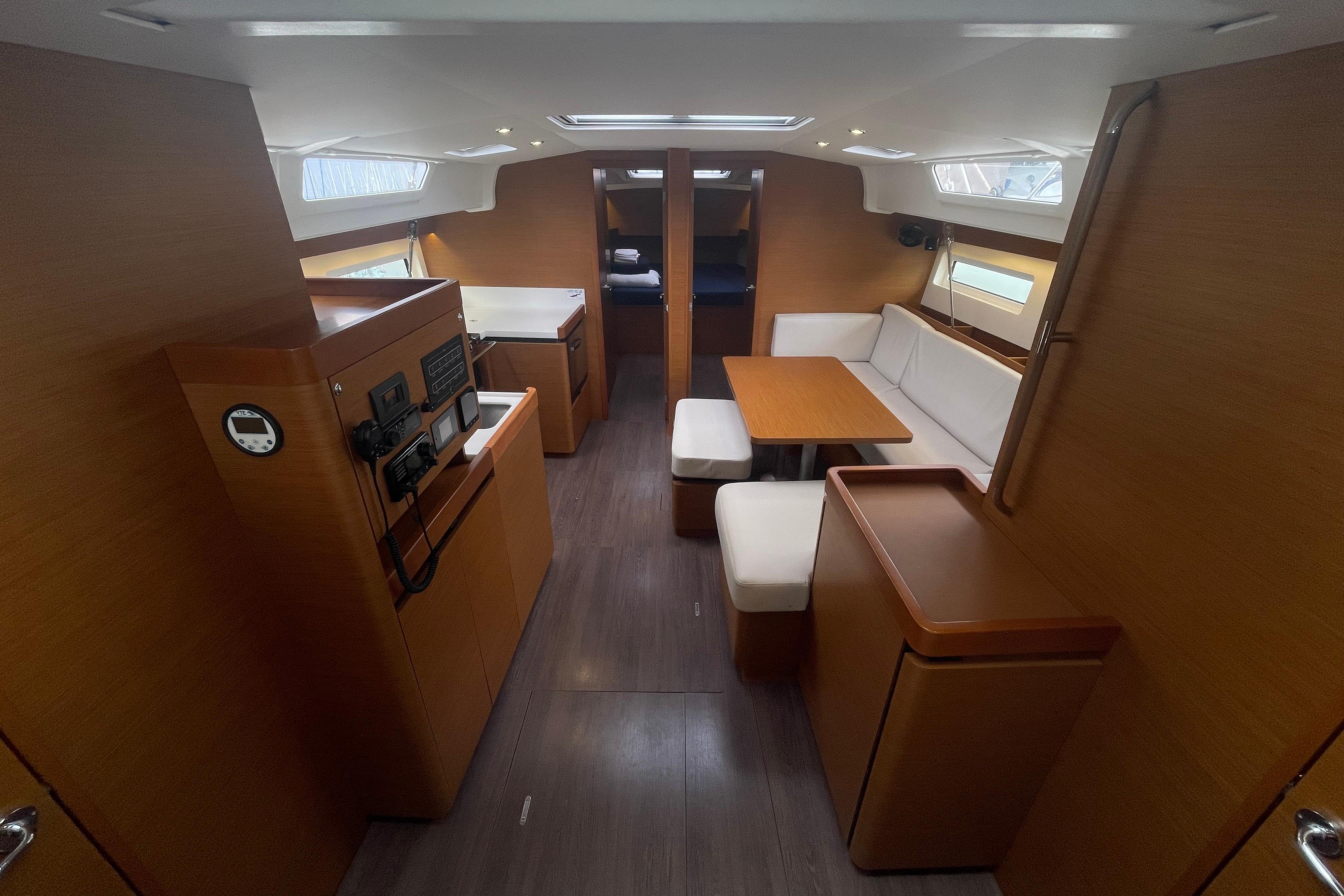 Interior of 2023 Jeanneau Sun Odyssey 490 yacht, featuring modern wood finish and cozy seating area.