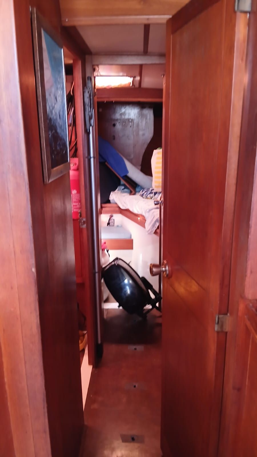 A narrow hallway inside a boat with wooden walls and an open door.