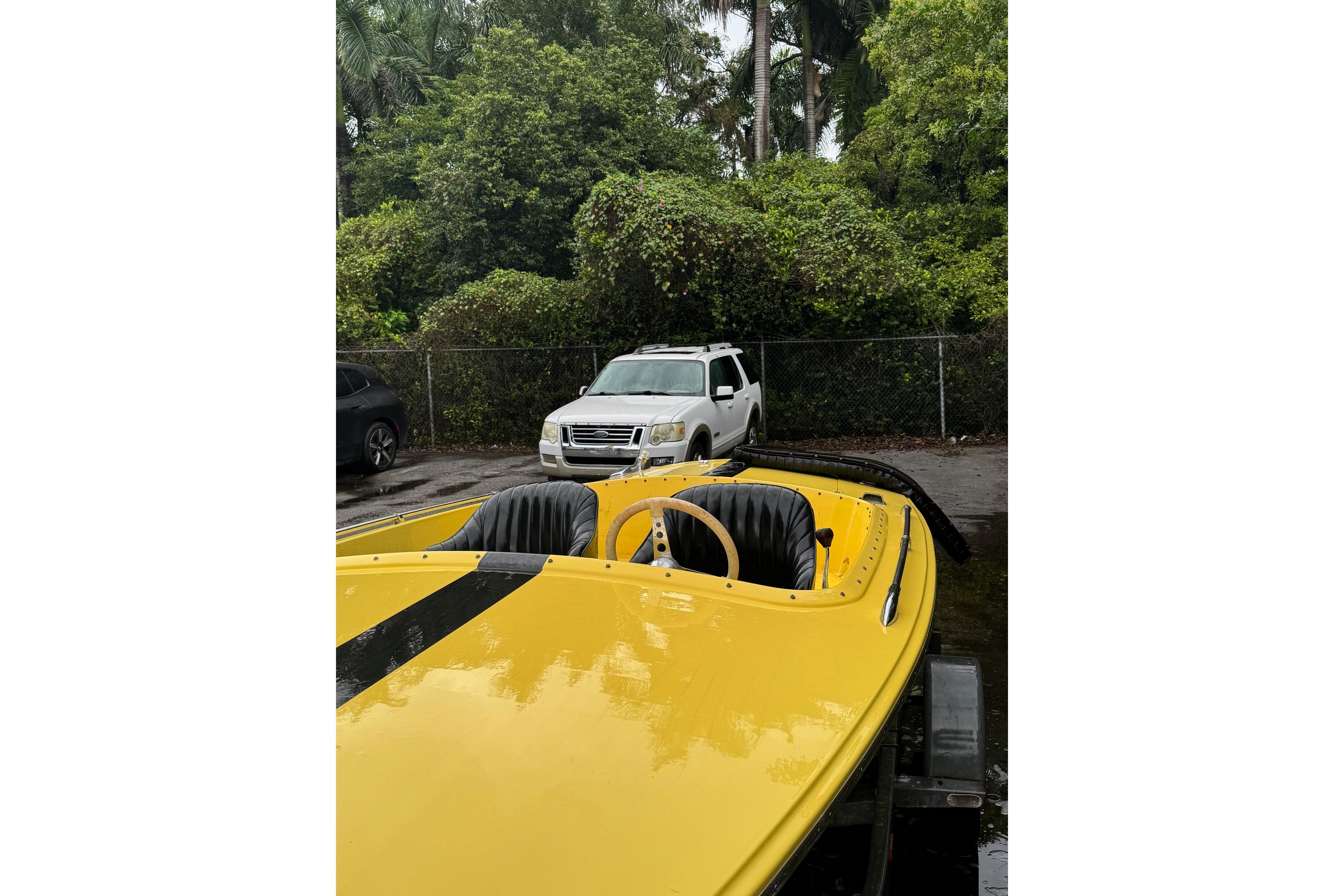 Yellow 1987 Donzi 16 Classic boat with black stripes, parked outdoors.