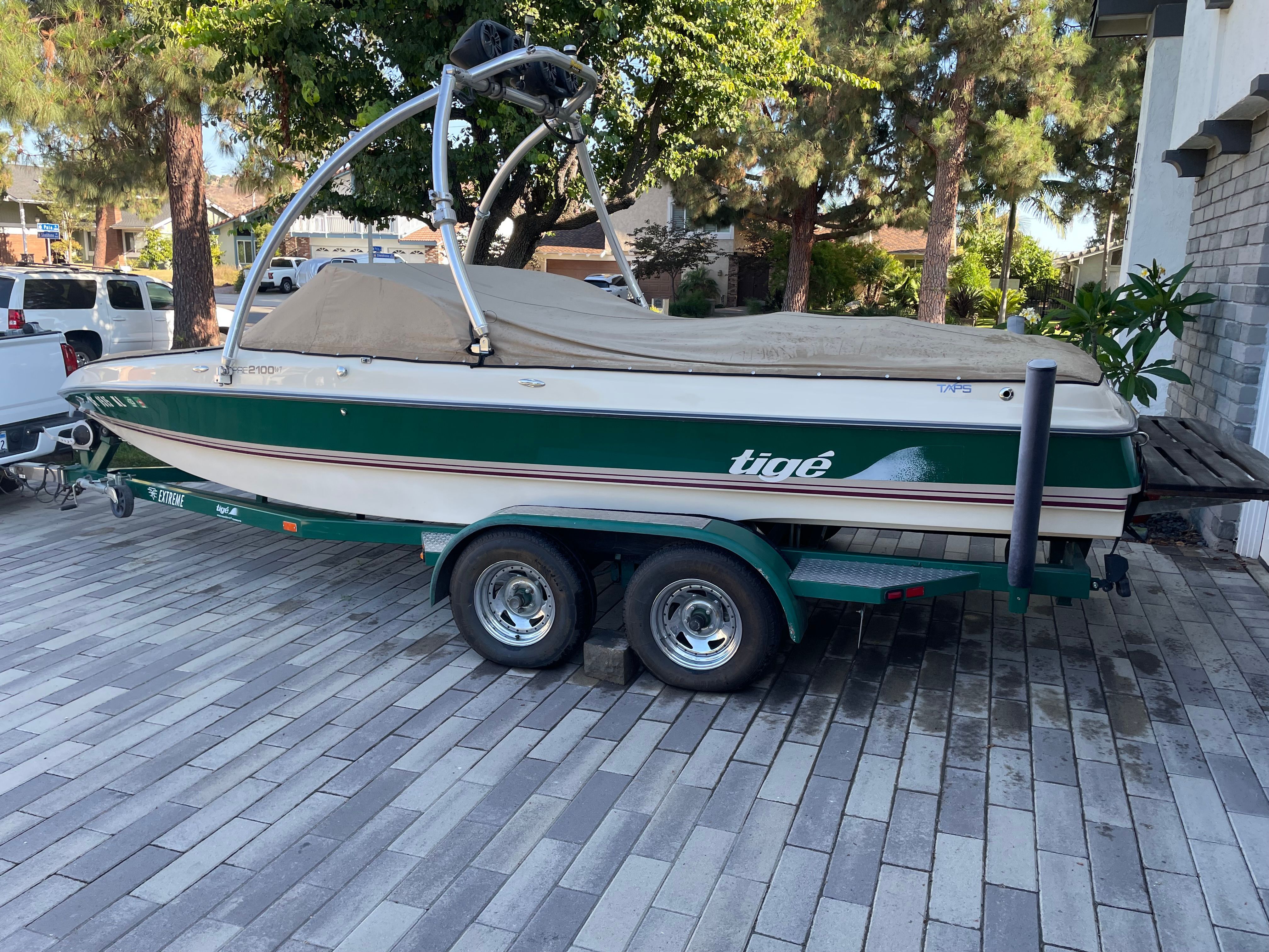 A green and white 1998 Tigé Pre 2100 boat is on a trailer.