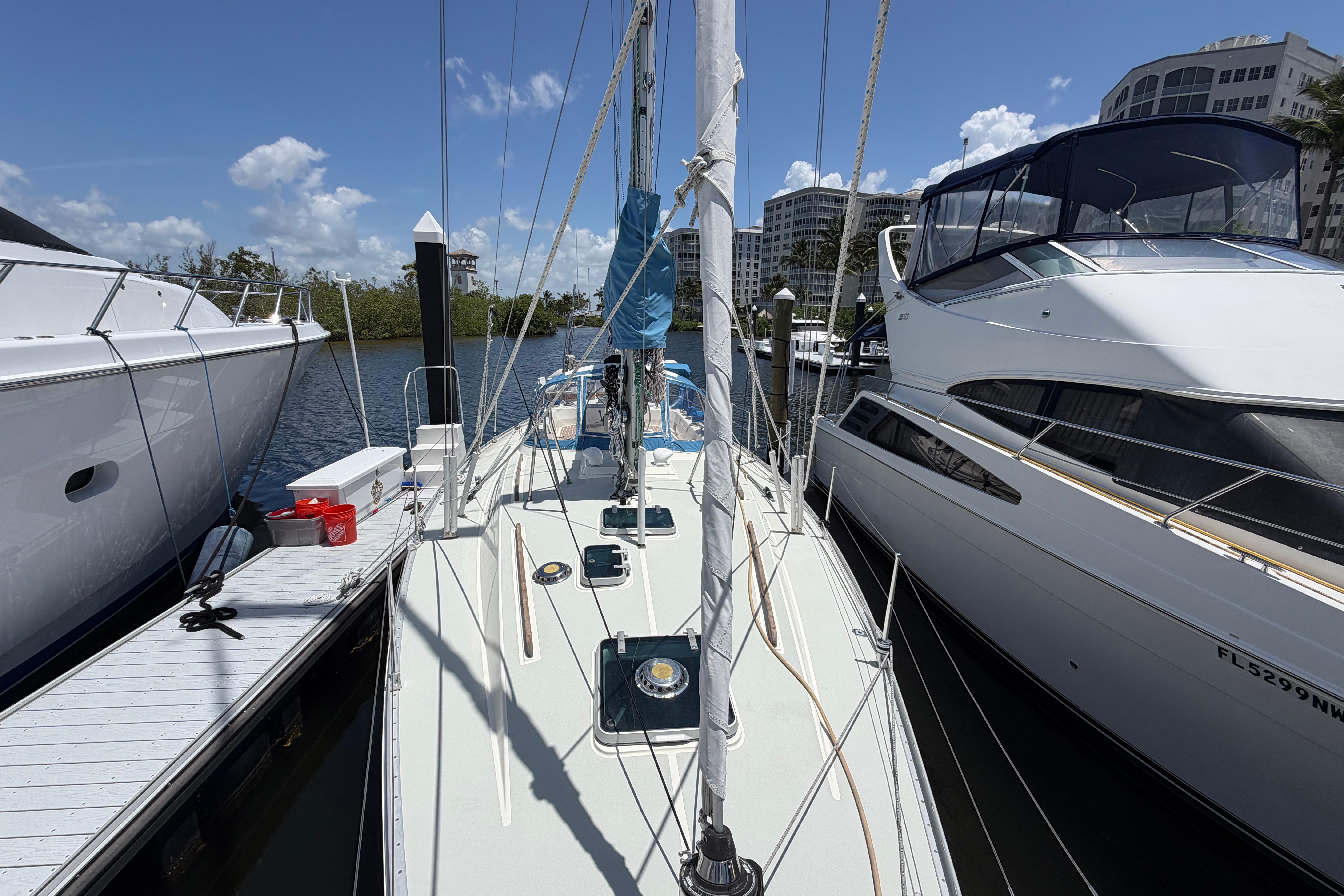 Sailboat Moody 376 (1987) docked between yachts, under clear blue skies.