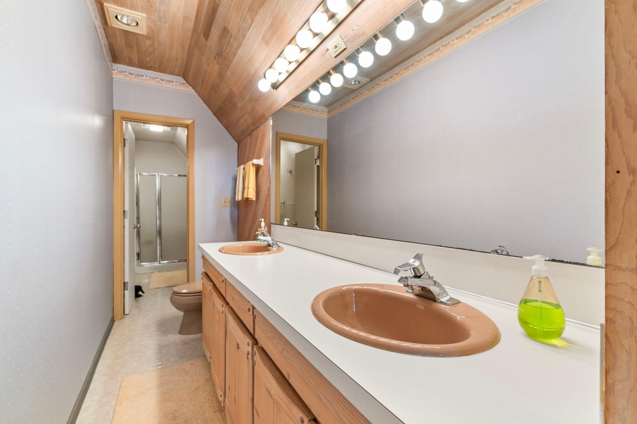 Vintage 1976 boathouse bathroom with dual sinks, large mirror, and wooden accents.
