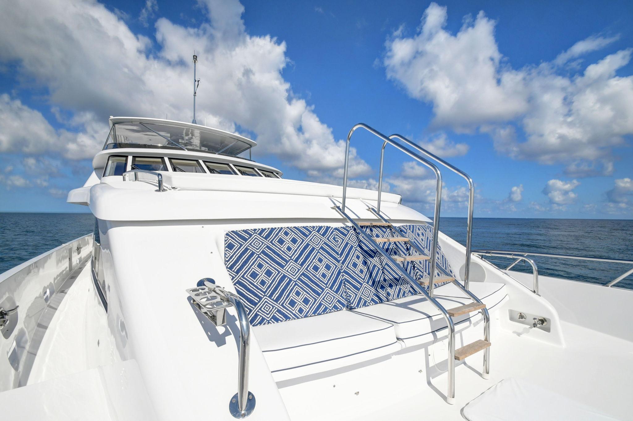 Hatteras 2005 Semi-Displacement yacht with blue patterned seating, under a clear sky.