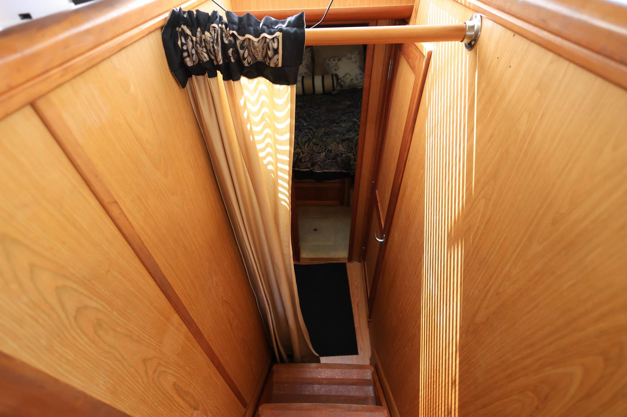 Interior view of 2005 Mainship 40 Trawler, featuring wooden stairs and cozy cabin entrance.